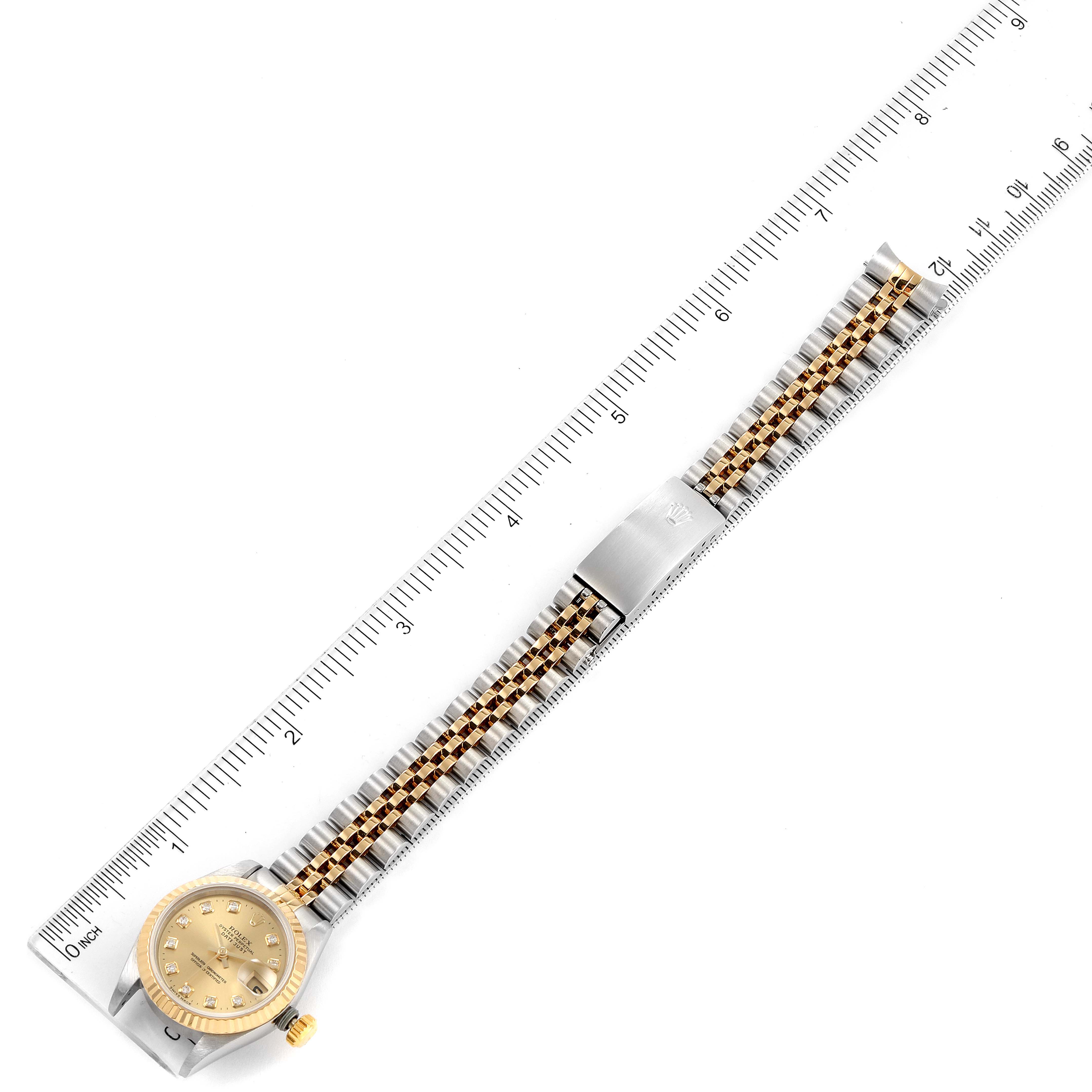 The image shows a Rolex Datejust 69173 Women's Steel and Gold (two tone) Champagne Dial 69173 Women's Steel and Gold (two tone) Champagne Dial watch placed along a ruler, displaying the gold dial and two-tone bracelet from an overhead angle.