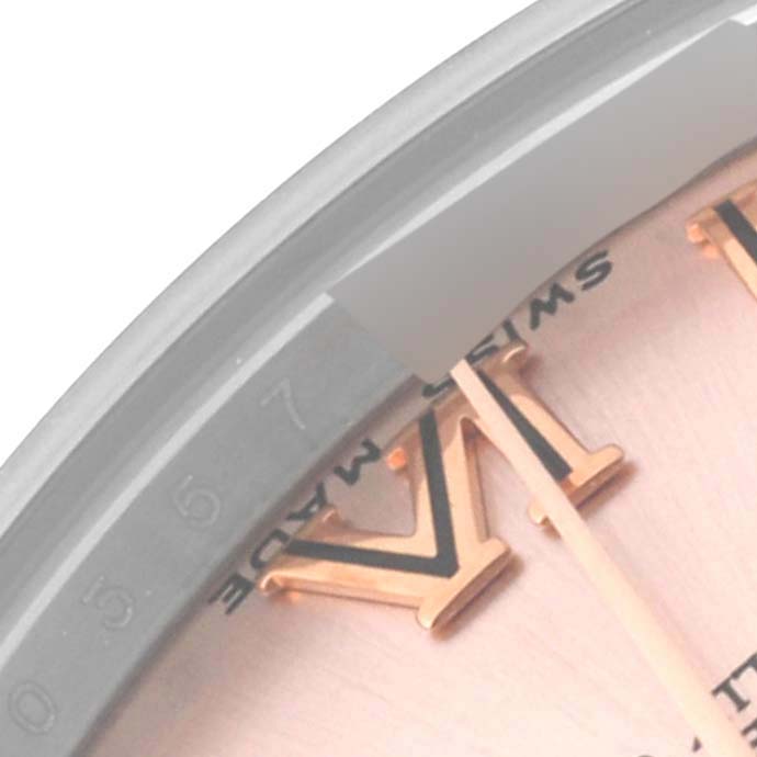 This close-up image of the Rolex Mid-Size 178241 Women's Steel and Gold (two tone) Pink Dial 178241 Women's Steel and Gold (two tone) Pink Dial model shows a portion of the dial, Roman numeral hour markers, and part of the crystal.