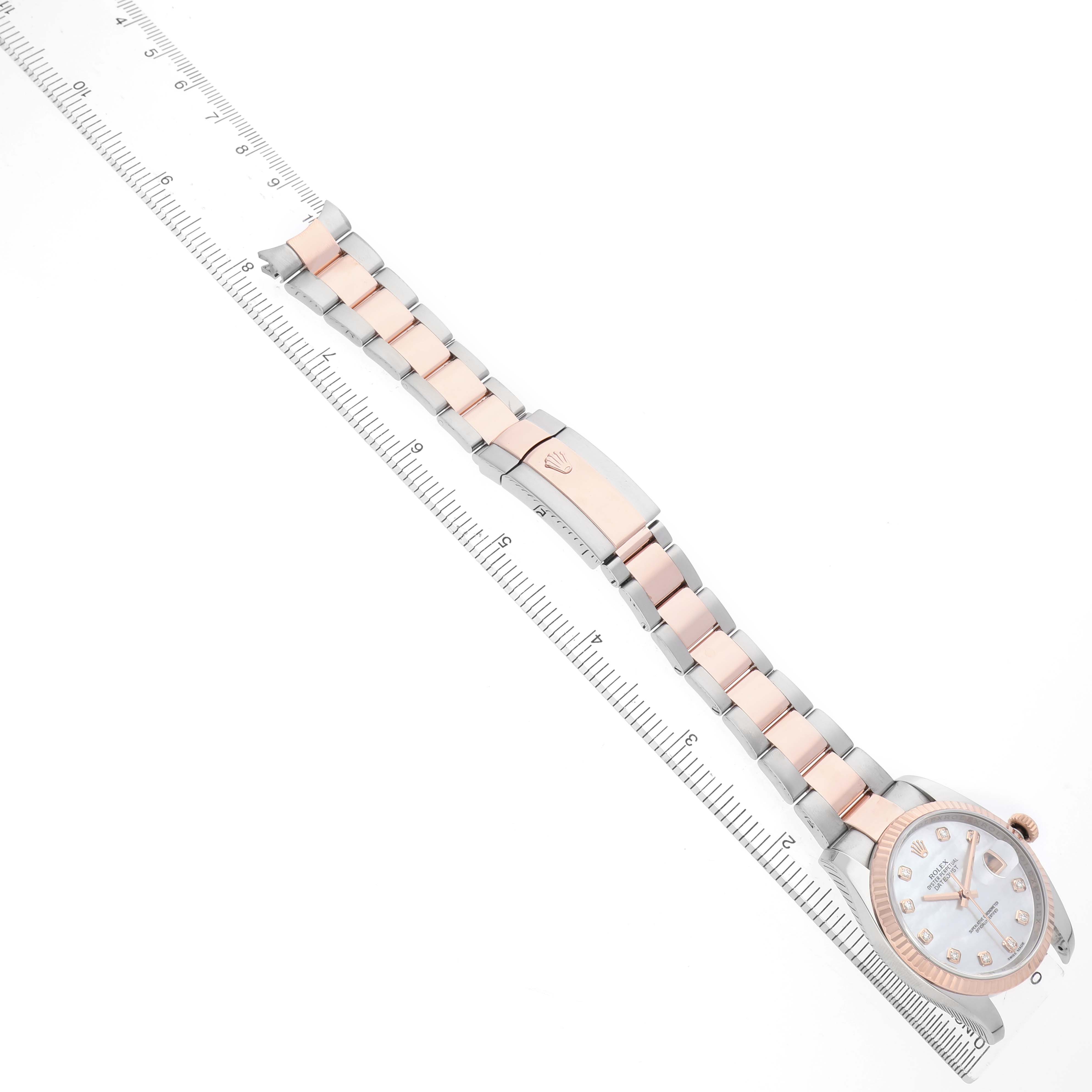The image shows a Rolex Datejust 116231 Men's Steel and Gold (two tone) Mother of Pearl Dial watch laid flat, displaying its full bracelet and clasp, alongside a measurement ruler.