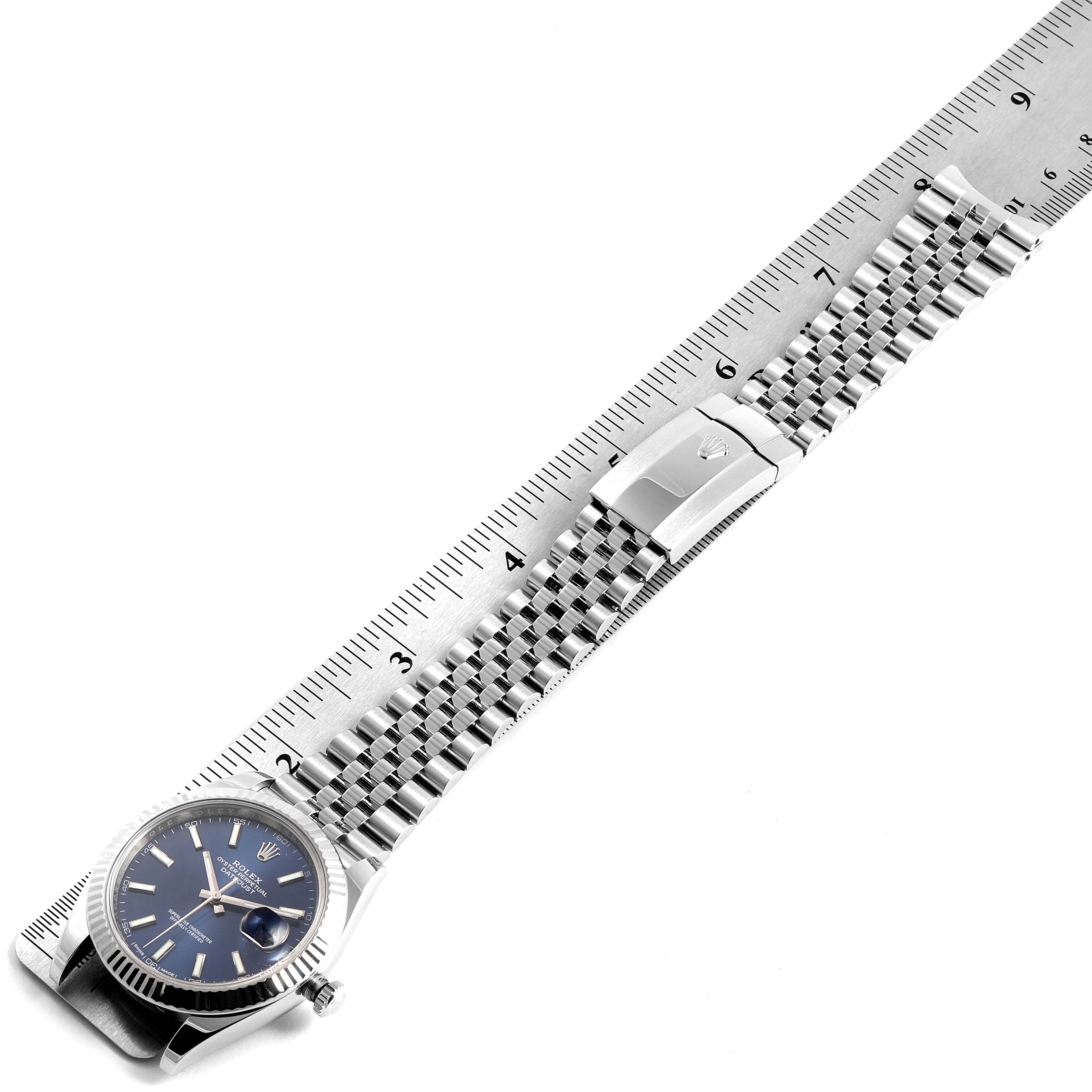 The Rolex Datejust 41 126334 Men's Stainless Steel Blue Dial 126334 Men's Stainless Steel Blue Dial watch is shown from a top-down angle, displaying its face, bracelet, and clasp alongside a ruler for scale.