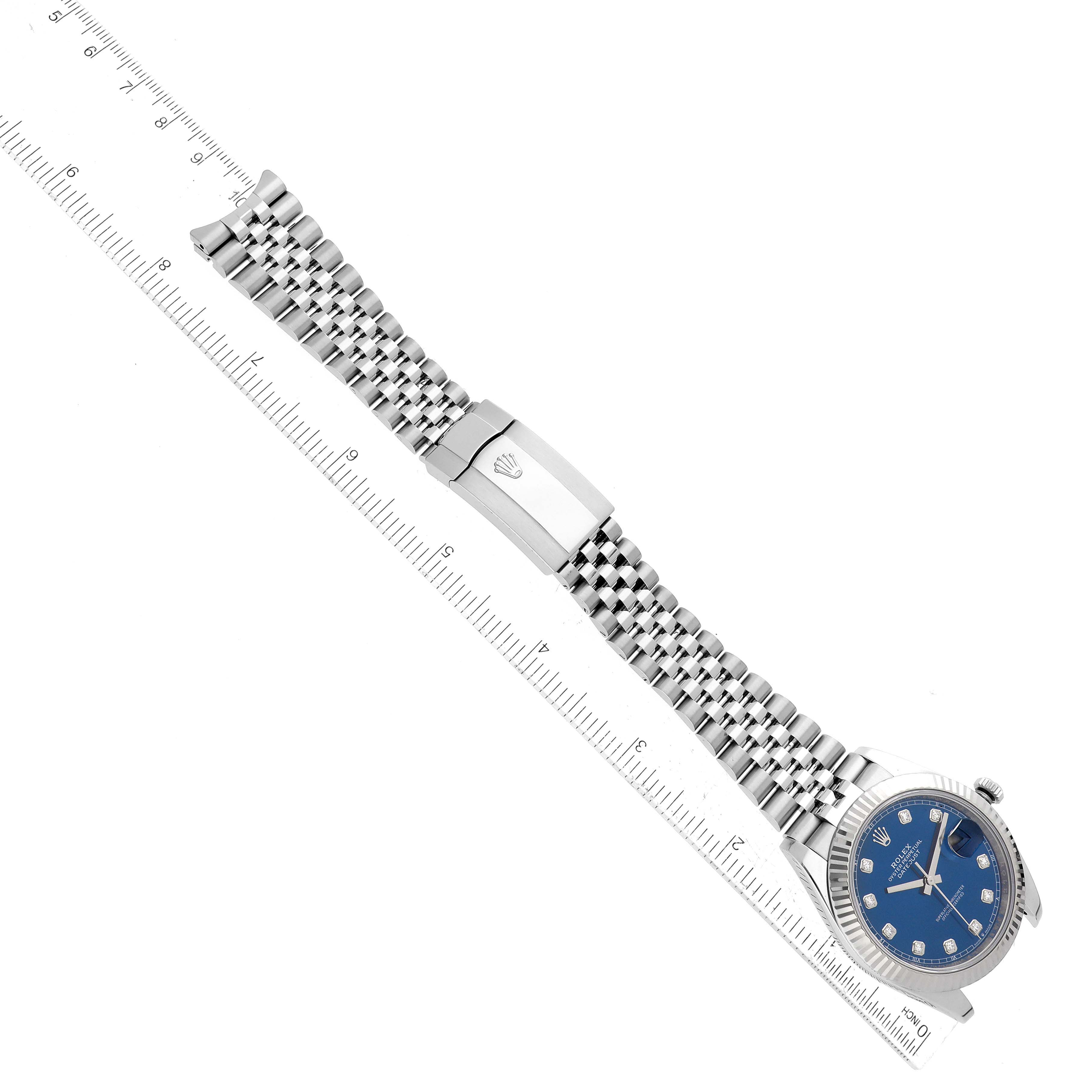 The image shows a Rolex Datejust 41 126334 Men
s Stainless Steel Blue Dial 126334 Men
s Stainless Steel Blue Dial watch laid flat with its blue dial, bracelet, and clasp visible, alongside a ruler for scale.