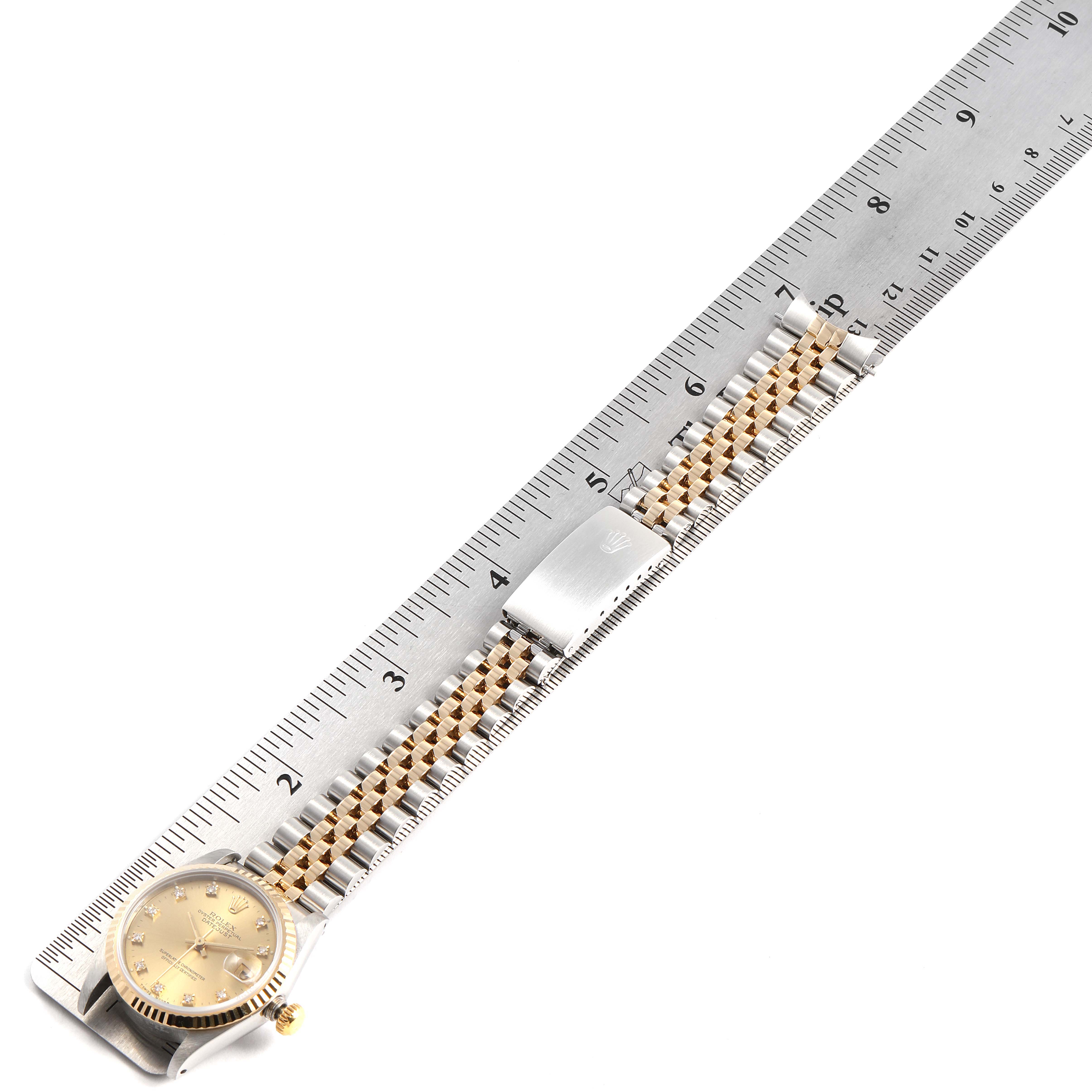The Rolex Mid-Size 68273 Women's Steel and Gold (two tone) Champagne Dial 68273 Women's Steel and Gold (two tone) Champagne Dial watch is displayed measuring its band with a ruler, showing the face, crown, and bracelet.