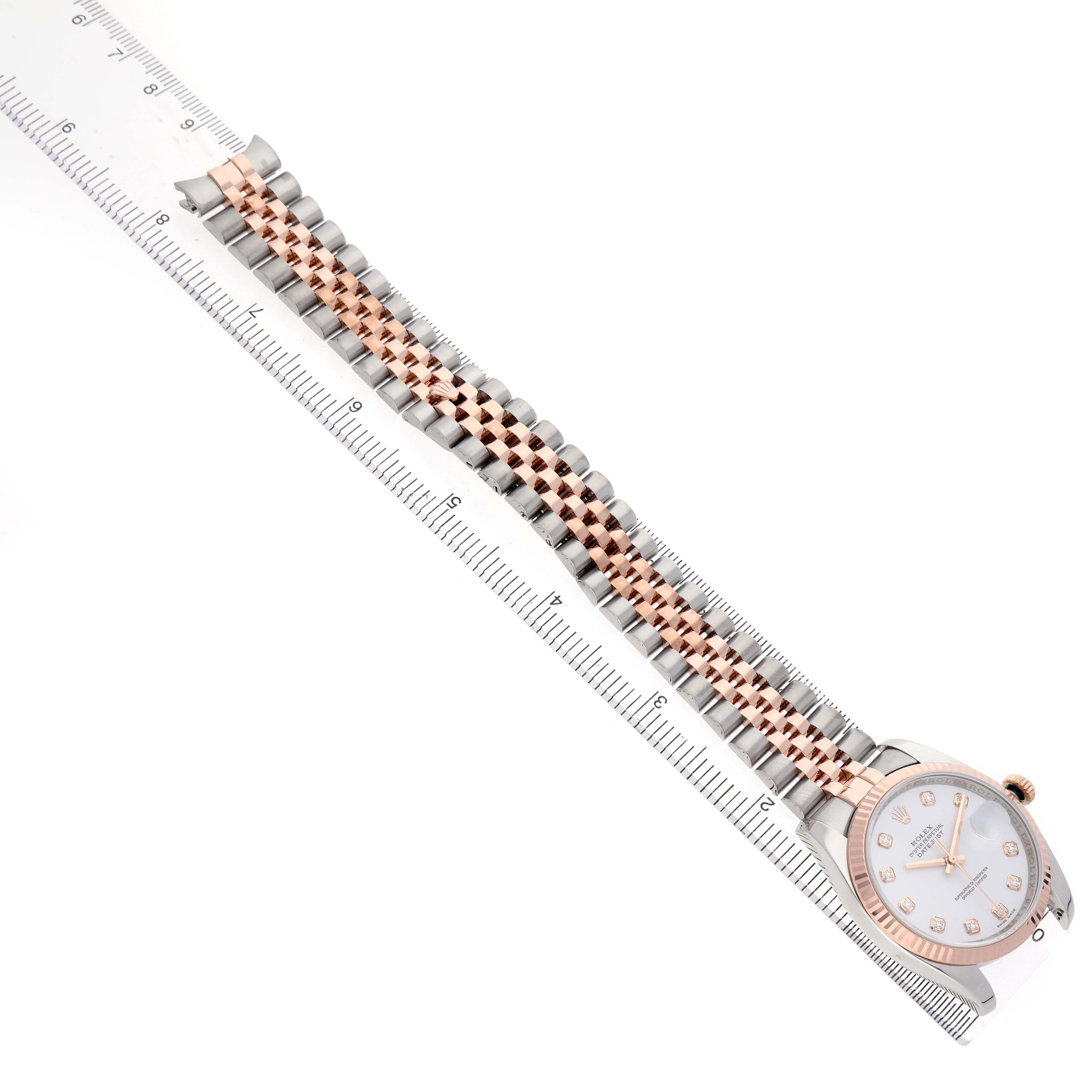 The Rolex Datejust 116231 Men's Steel and Gold (two tone) White Dial watch is shown at an angled top view, displaying the face and full bracelet beside a ruler.