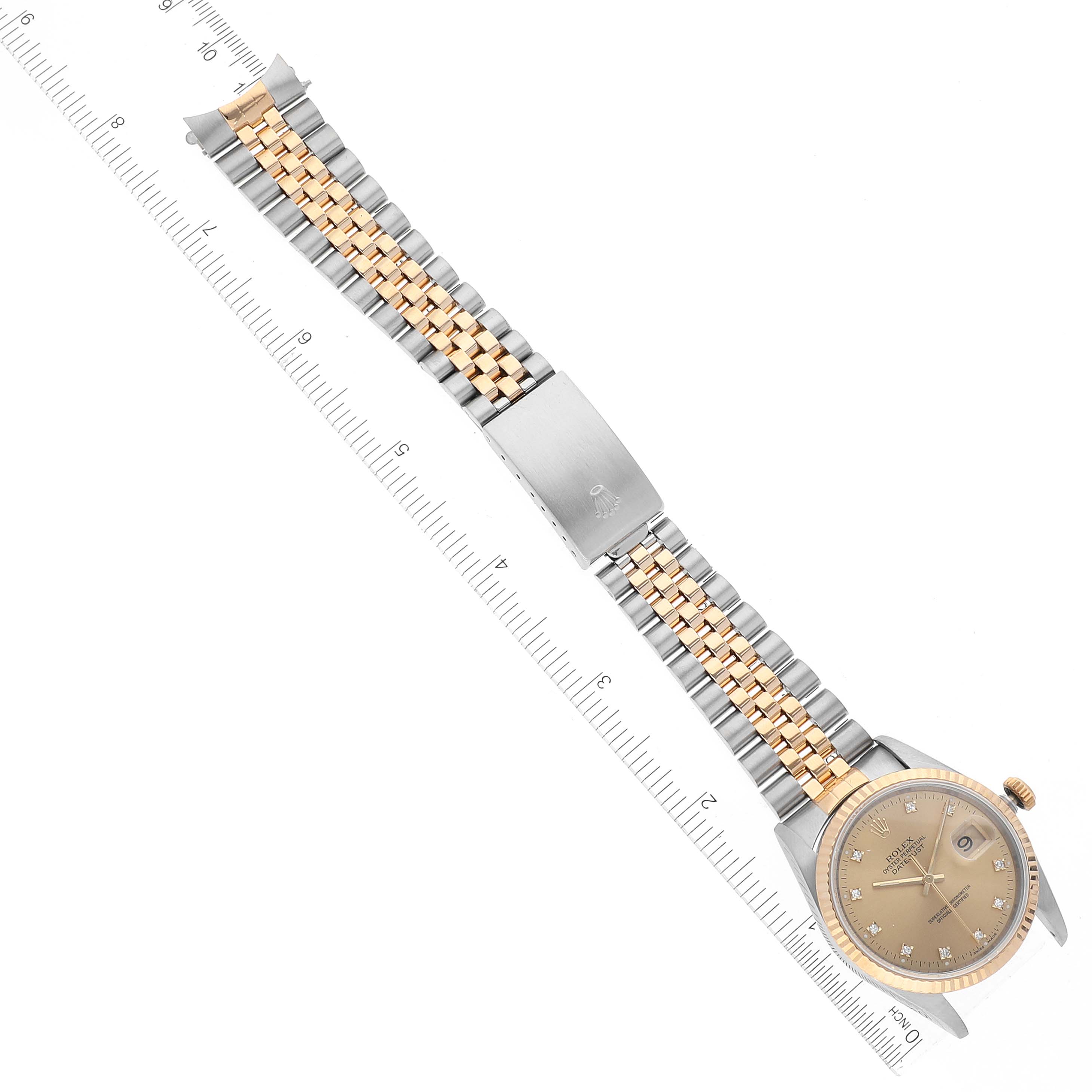The Rolex Datejust 16233 Men's Steel and Gold (two tone) Champagne Dial 16233 Men's Steel and Gold (two tone) Champagne Dial watch is shown from a top-down angle, displaying the full strap, clasp, and watch face aligned with a measuring ruler.