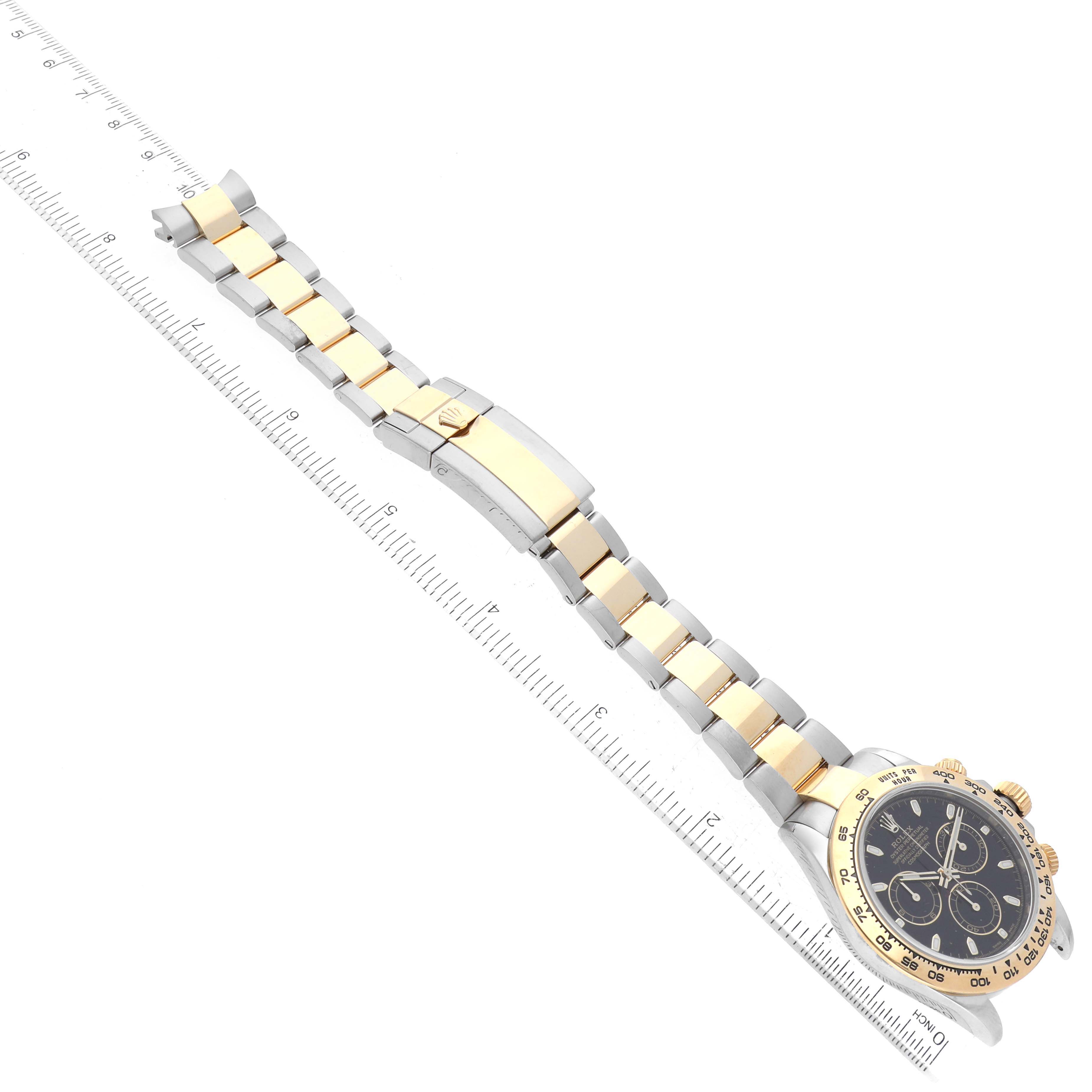 The image shows a top-down view of a Rolex Daytona 116503 Men's Steel and Gold (two tone) Black Dial 116503 Men's Steel and Gold (two tone) Black Dial watch, focusing on its two-tone bracelet and clasp alongside a ruler for measurement.