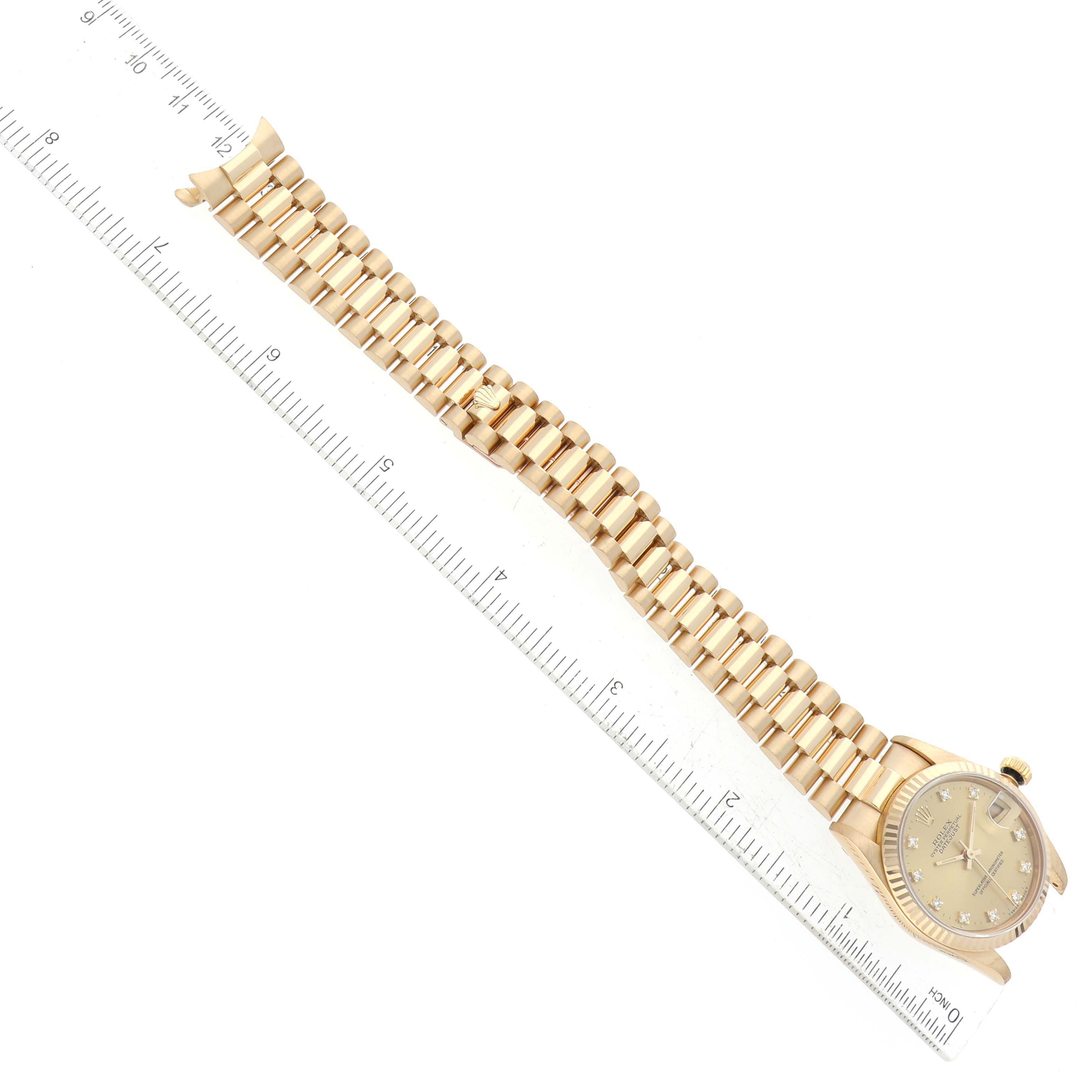 This image shows a Rolex President 68278 Women's Yellow Gold Champagne Dial 68278 Women's Yellow Gold Champagne Dial model watch laid flat alongside a ruler, highlighting its bracelet and case.