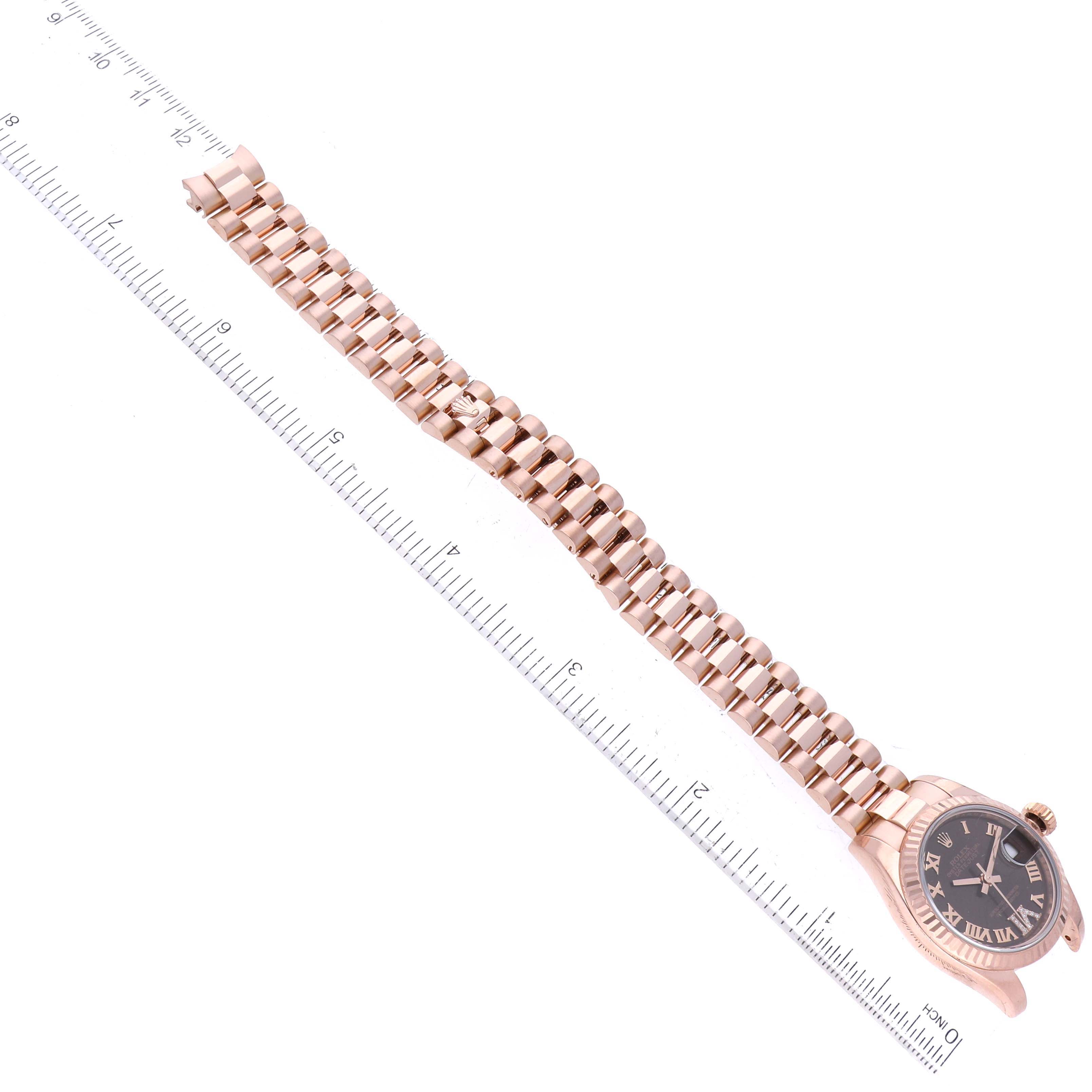 The image shows a top-down view of a Rolex President 179175 Women's Rose Gold Brown Dial 179175 Women's Rose Gold Brown Dial model watch, displaying the watch face and full bracelet alongside a ruler.