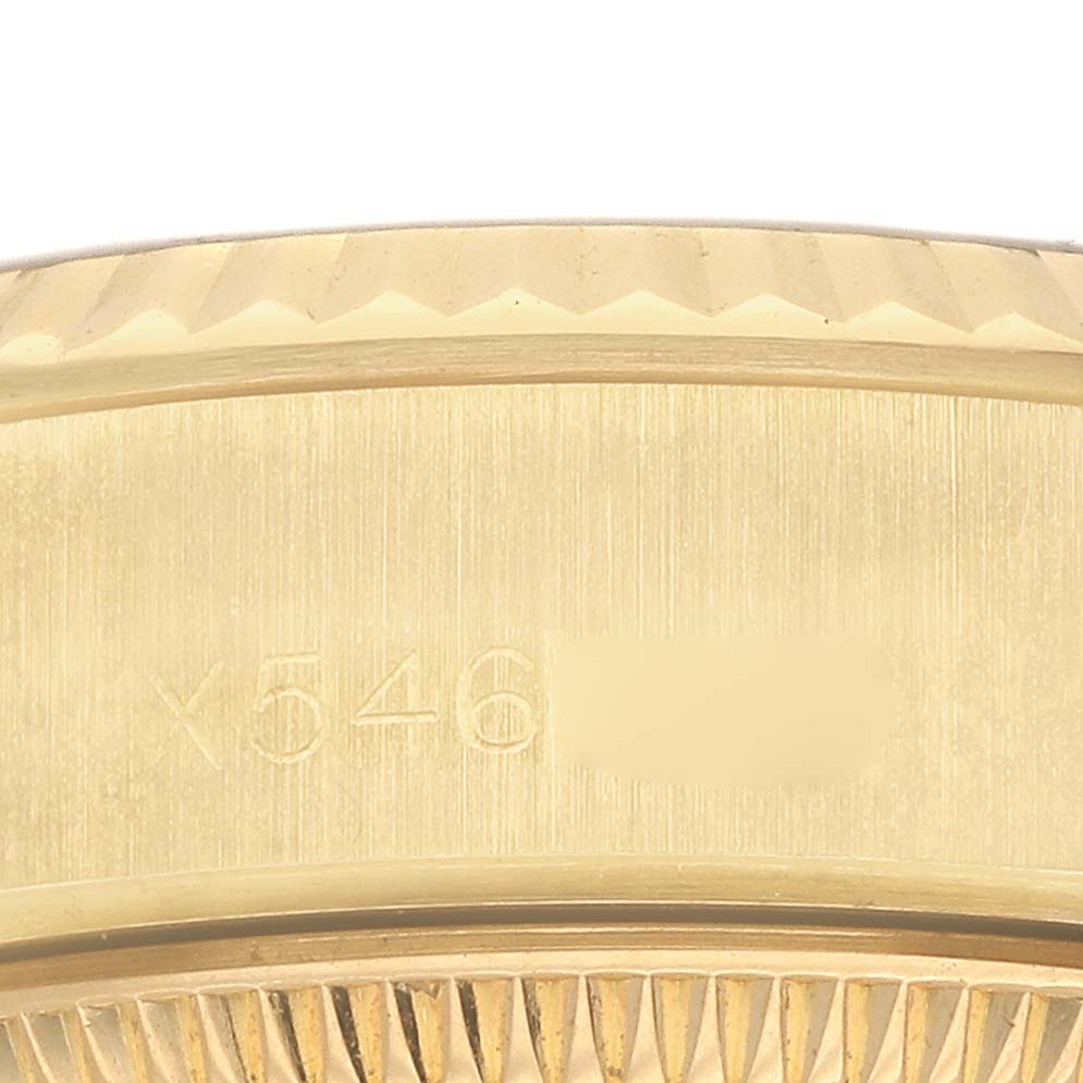 The image shows a close-up of the Rolex President 69178 Women's Yellow Gold Champagne Dial watch's fluted bezel and part of its engraved case side.