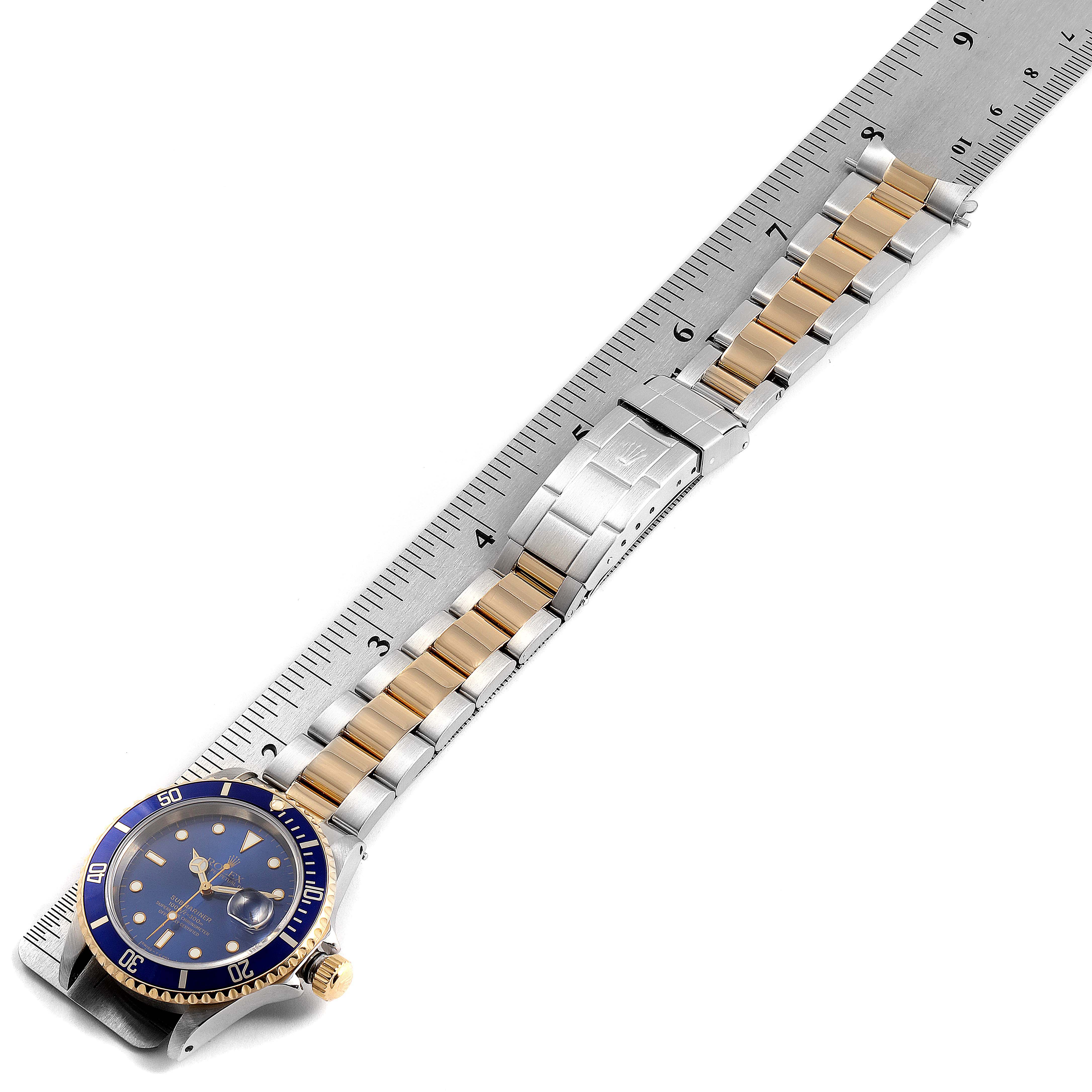 The Rolex Submariner 16613 Men
s Steel and Gold (two tone) Blue Dial 16613 Men
s Steel and Gold (two tone) Blue Dial watch is shown at an angled top-down view, featuring its blue dial, gold and silver bracelet, and clasp.