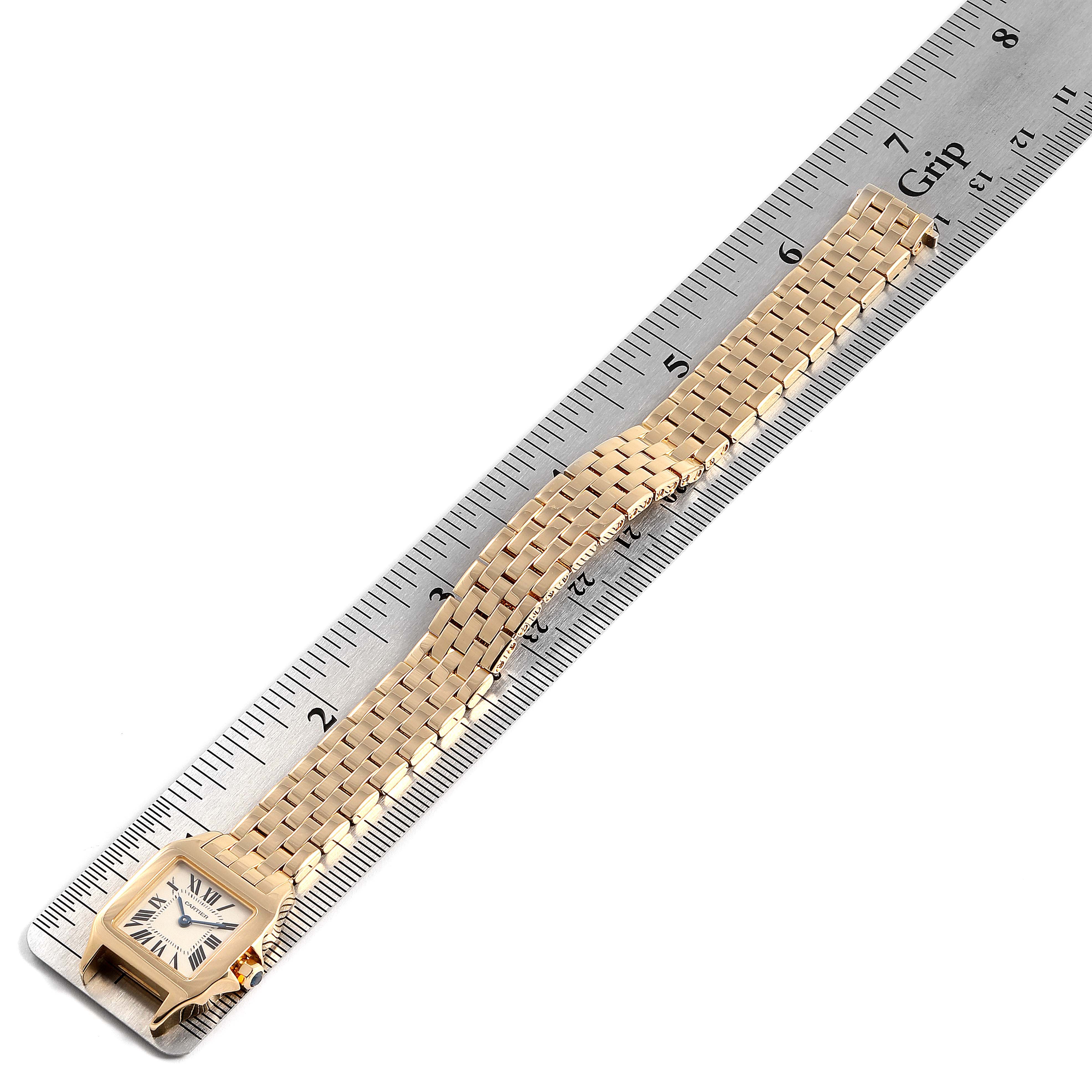 The Cartier Santos Demoiselle W25063X9 Women's Yellow Gold Silver Dial W25063X9 Women's Yellow Gold Silver Dial watch is shown from a top-down angle, displaying its face and full bracelet alongside a ruler for scale.