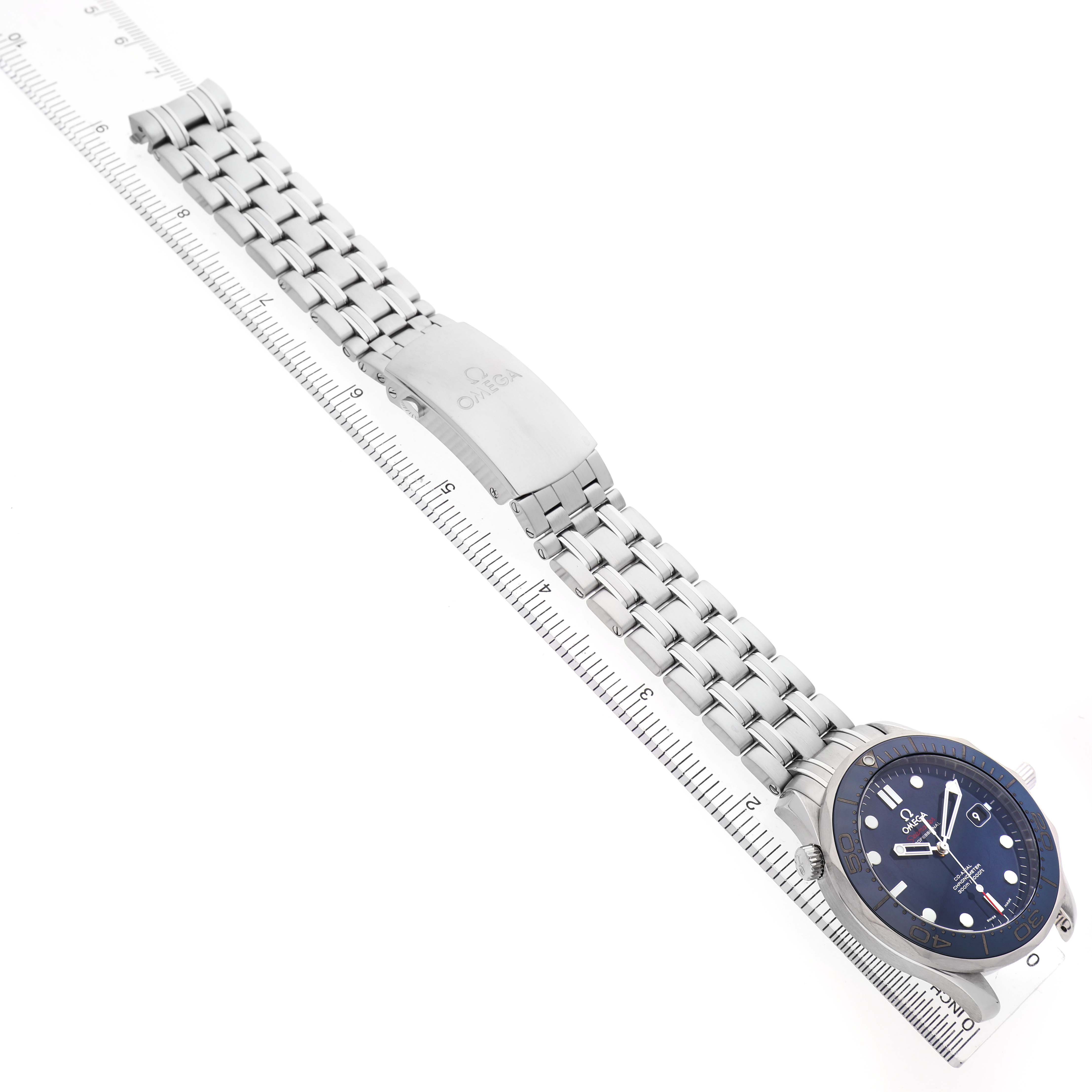 The Omega Seamaster 212.30.41.20.03.001 Mens Stainless Steel Blue Dial watch is shown from a top angle, featuring the bracelet, clasp, and dial with a ruler underneath for scale.