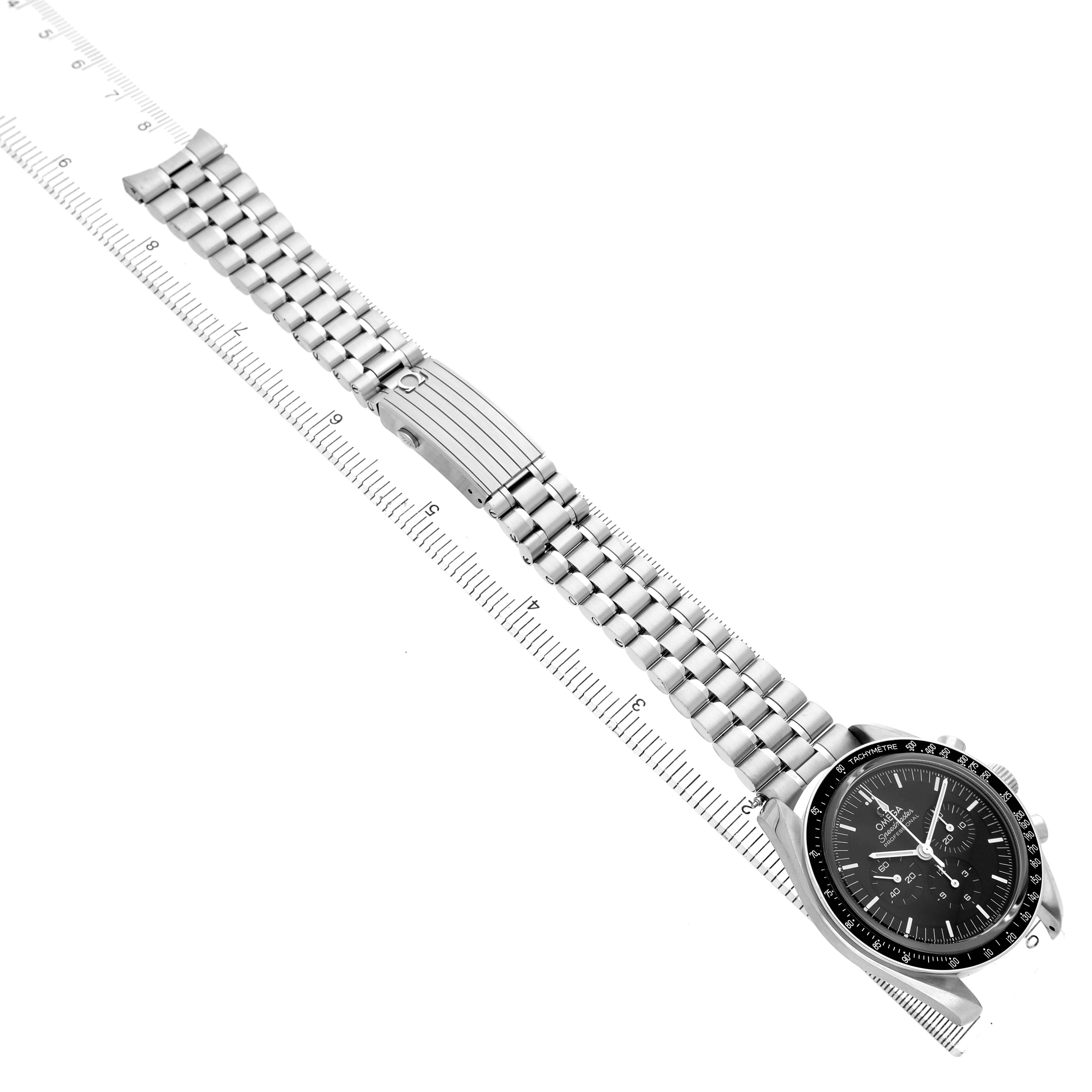 The Omega Speedmaster 310.32.42.50.01.002 Mens Stainless Steel Black Dial watch is shown at a top-down angle, highlighting the face and entire metal bracelet on a ruler.