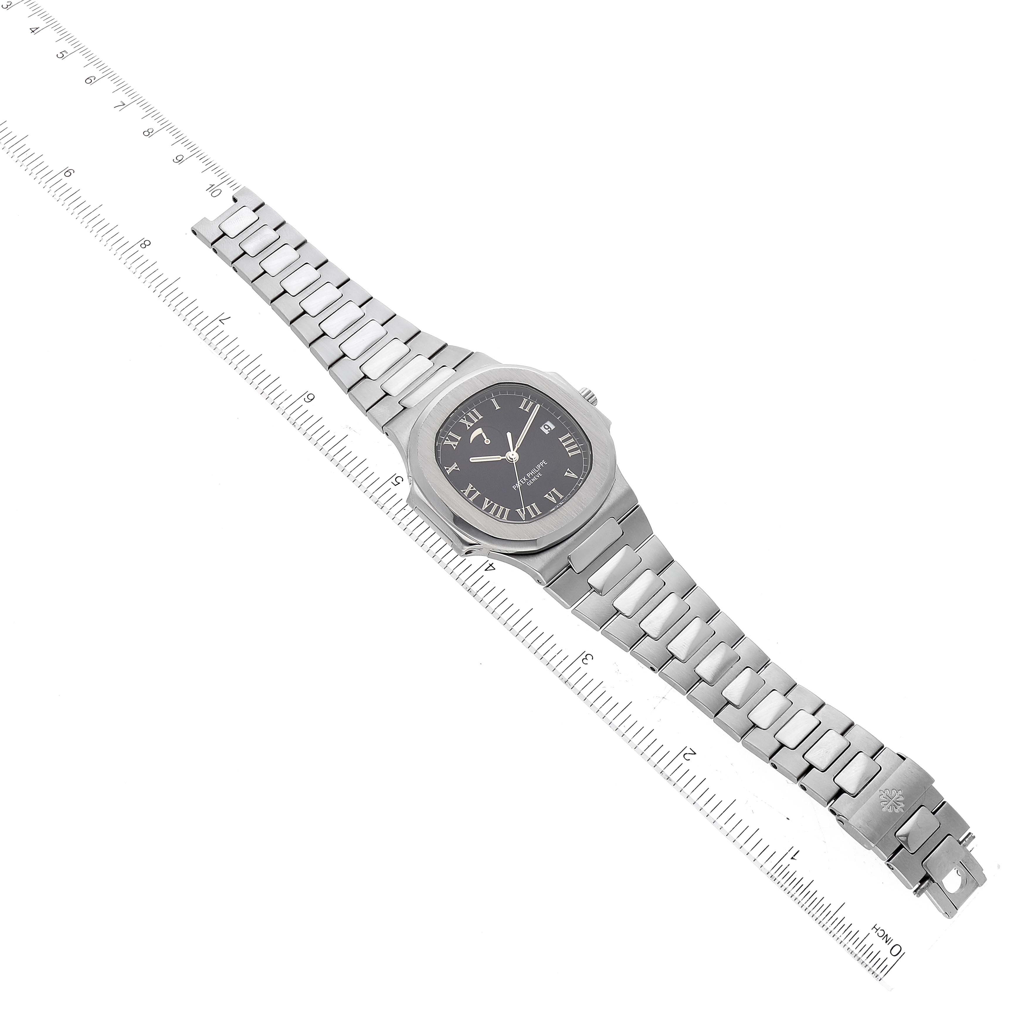 This image shows a Patek Philippe Nautilus 3710/1A Men's Stainless Steel Black Dial 3710/1A Men's Stainless Steel Black Dial watch laid flat with its face and metal bracelet fully visible, alongside a ruler for scale.