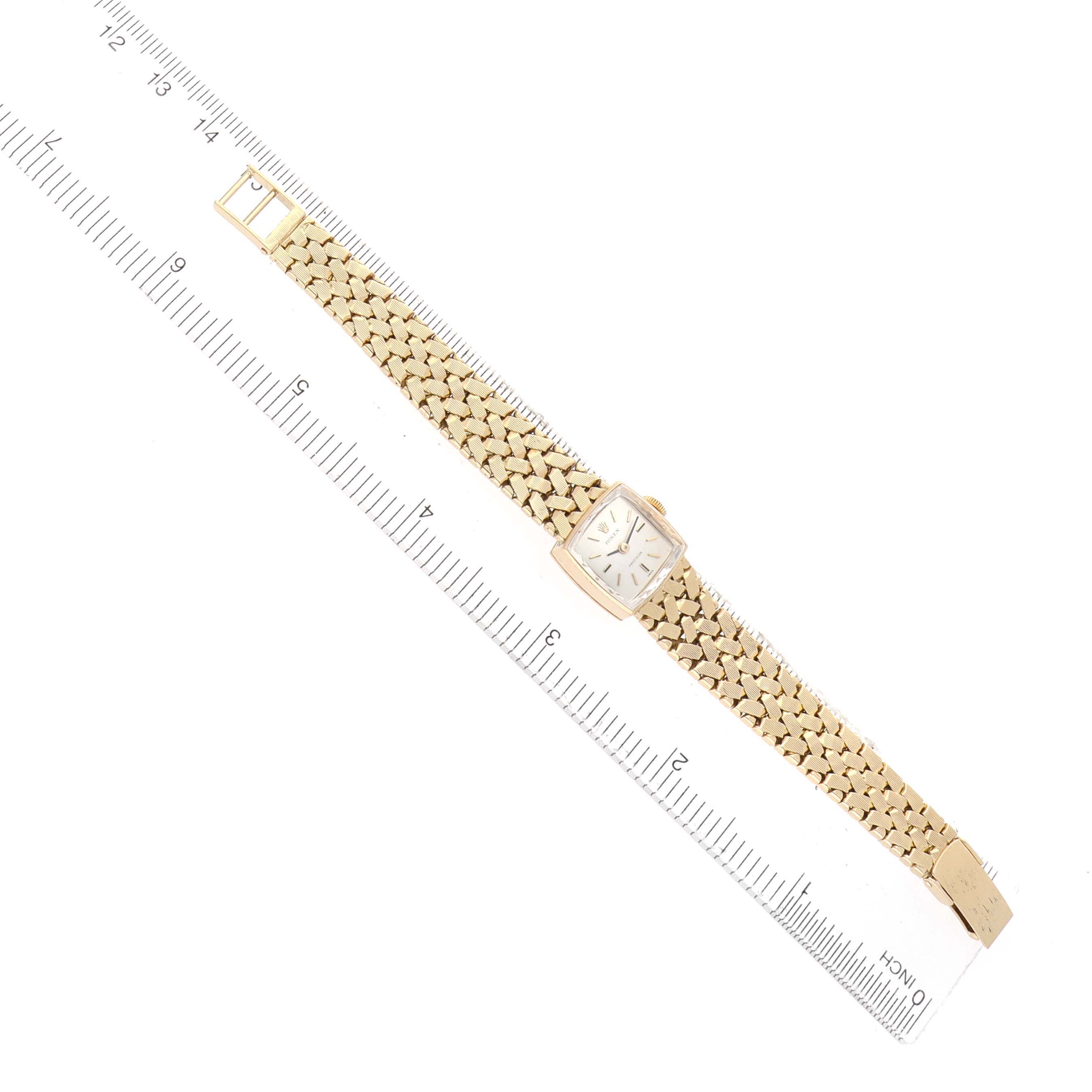 The Rolex Cocktail 8298 Women's Yellow Gold Silver Dial model watch is shown laid flat with its face and entire bracelet visible next to a ruler for scale.