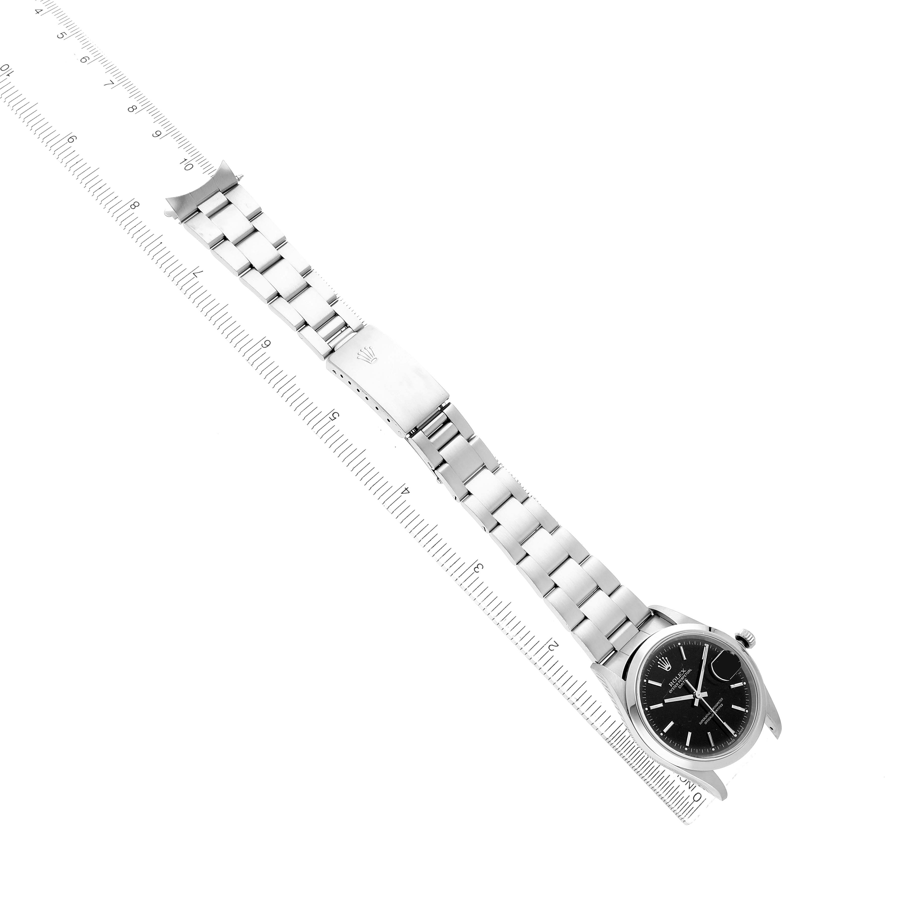 The Rolex Date 15200 Men's Stainless Steel Black Dial watch is shown from a top-down angle, displaying the face, bracelet, and clasp alongside a ruler for scale.