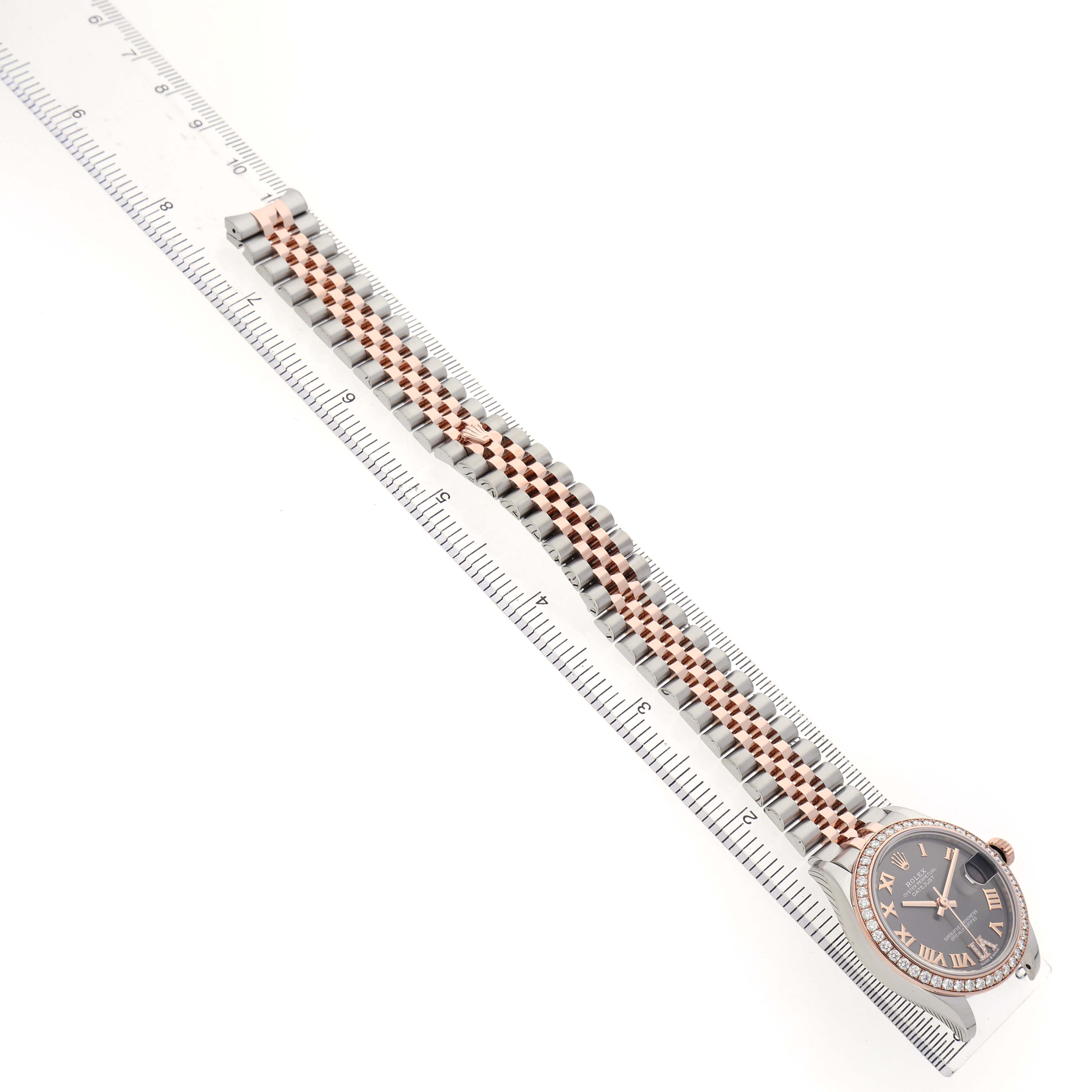 The Rolex Mid-Size 278381RBR-0020 Womens Stainless Steel Grey Dial watch is photographed from a top-down angle, showing the full bracelet and face alongside a ruler.