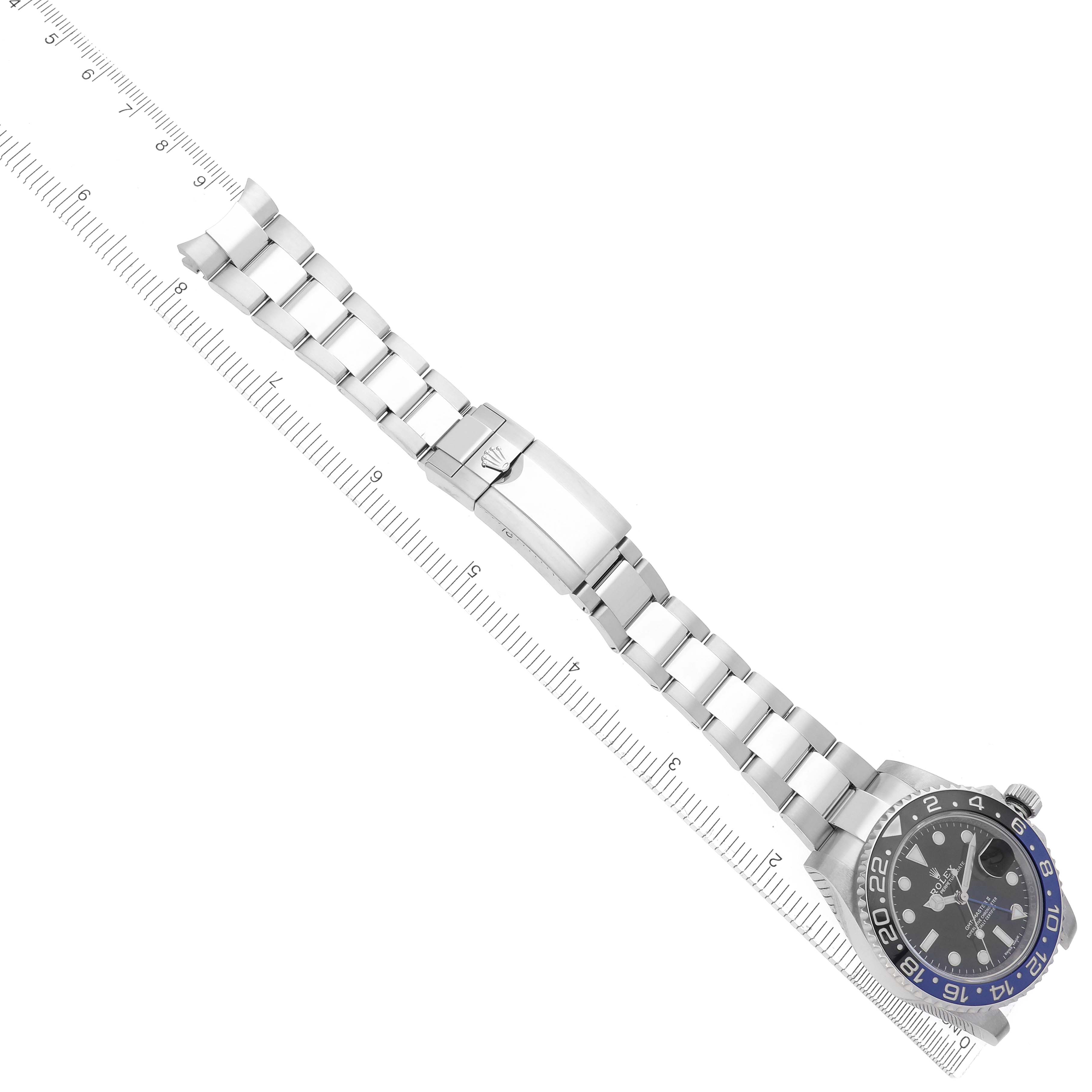 The Rolex GMT-Master 116710BLNR Men's Stainless Steel Black Dial watch is shown from a top view, highlighting the bracelet, clasp, and case with a ruler for scale.