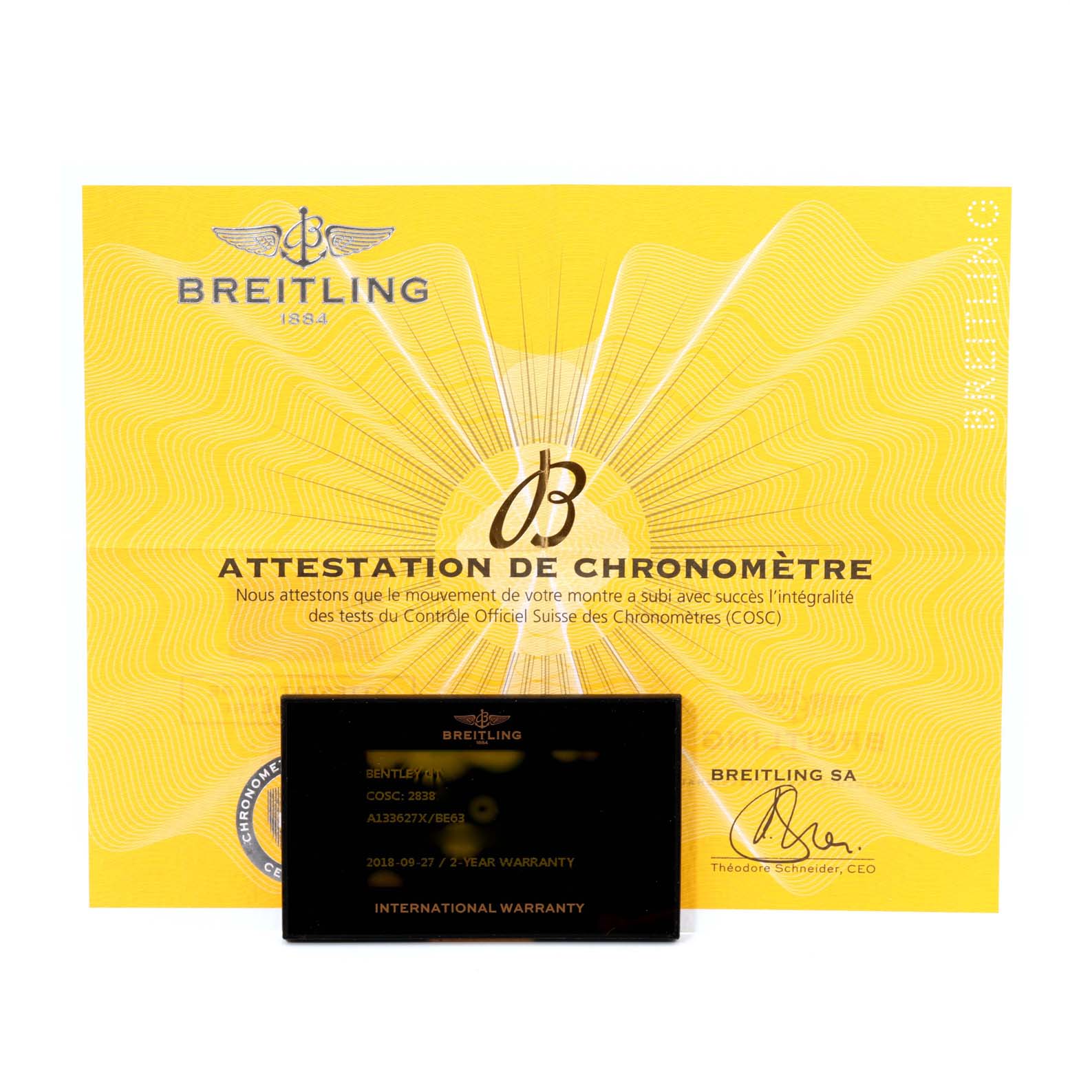 The image shows a yellow Breitling chronometer certification and a black international warranty card for the Bentley model by Breitling.