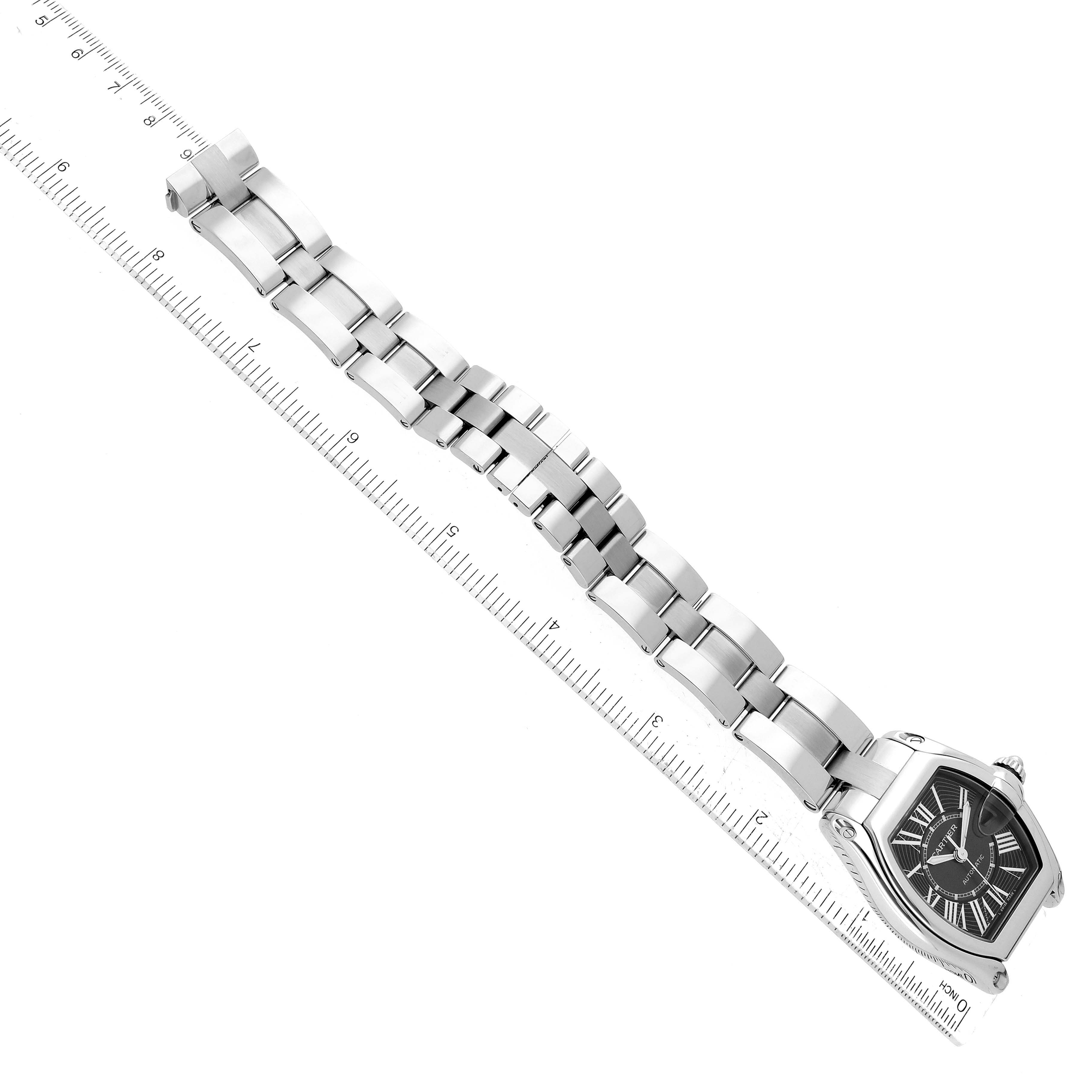 The image shows a Cartier Roadster W62041V3 Men's Stainless Steel Black Dial W62041V3 Men's Stainless Steel Black Dial watch with its band fully extended and measured against a ruler, viewed from an angled top-down perspective.