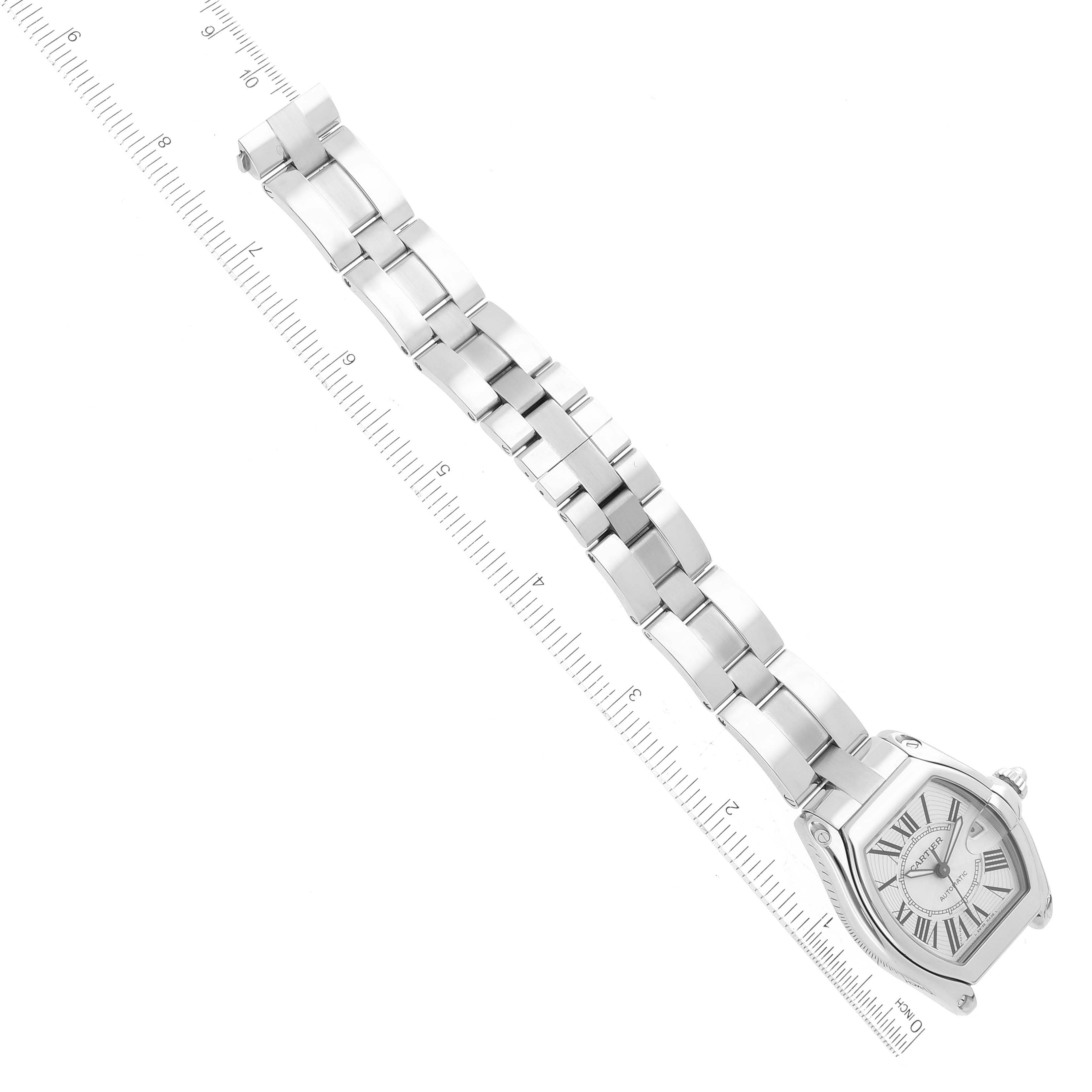 The image shows the Cartier Roadster W62025V3 Men's Stainless Steel Silver Dial W62025V3 Men's Stainless Steel Silver Dial watch at a diagonal angle, displaying the face and stainless steel bracelet against a ruler for scale.