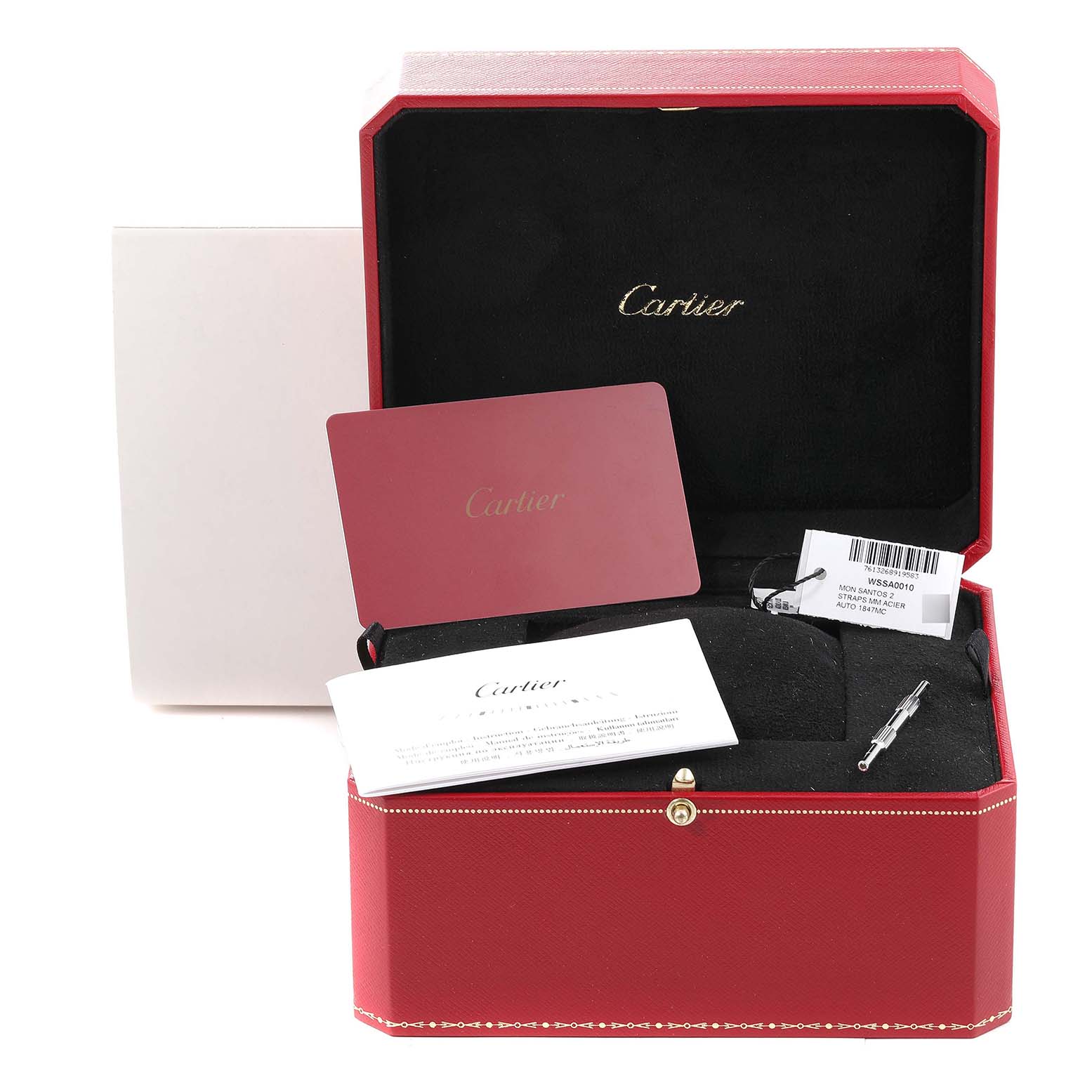The image shows a Cartier Santos WSSA0010 Men's Stainless Steel Silver Dial WSSA0010 Men's Stainless Steel Silver Dial watch box with accessories, including a card, documentation, and a tool, viewed from an angled top-down perspective.