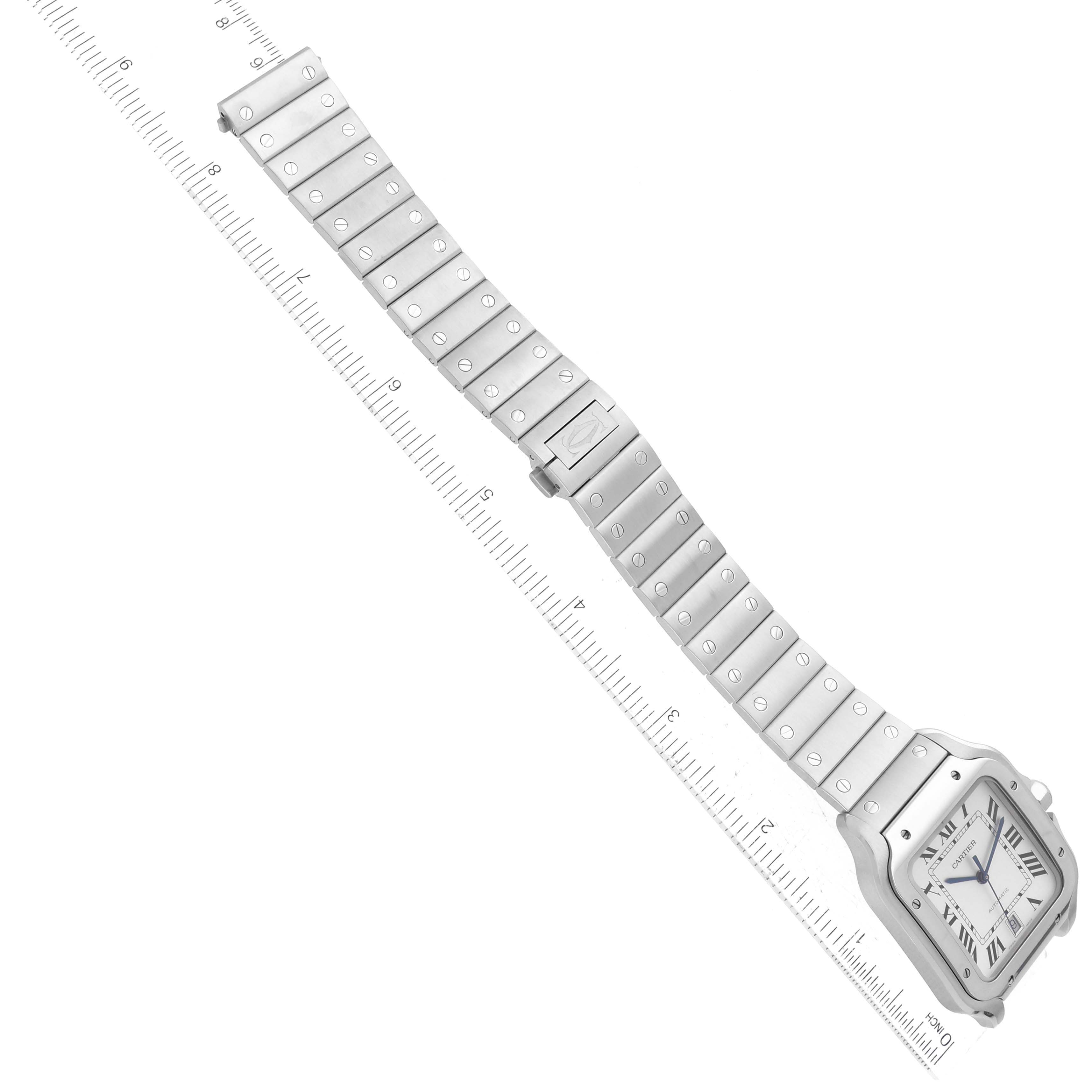 The image shows a Cartier Santos WSSA0009 Men
s Stainless Steel Silver Dial WSSA0009 Men
s Stainless Steel Silver Dial watch laid flat with its metal bracelet extended alongside a ruler for scale.