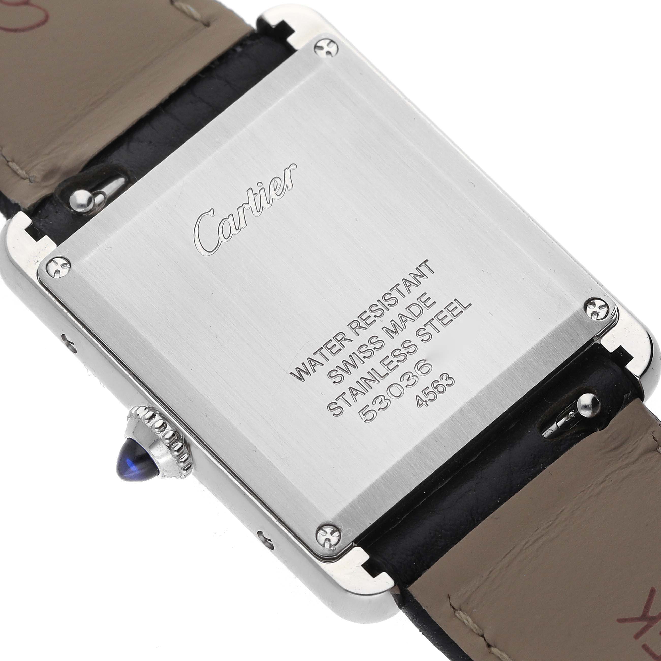 The image shows the back of the Cartier Tank Must WSTA0120 Men's Stainless Steel Silver Dial watch, highlighting the case back inscriptions and part of the strap.