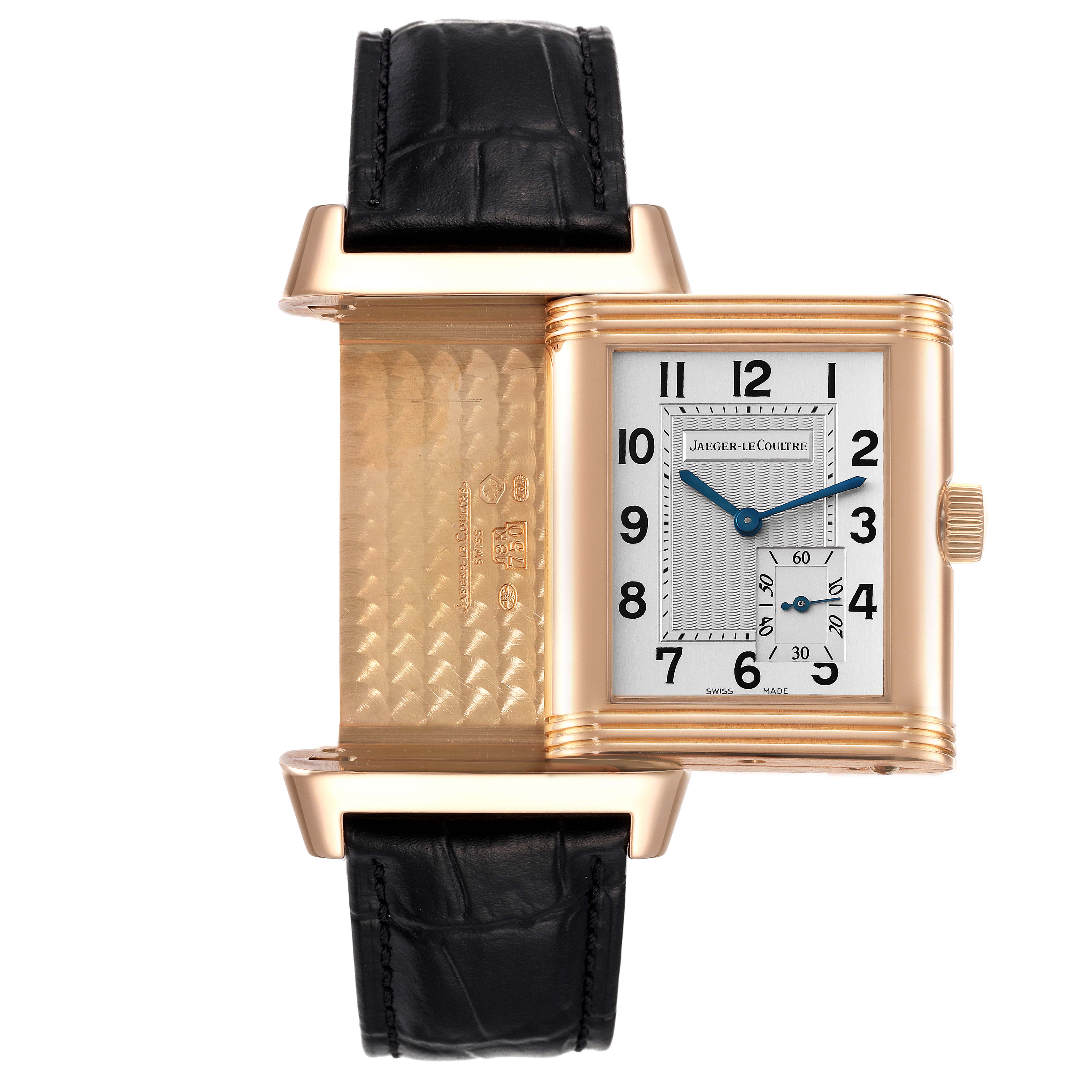 The Jaeger-LeCoultre Reverso watch is shown at an open angle, revealing both its dial and reverse side with detailed engravings.