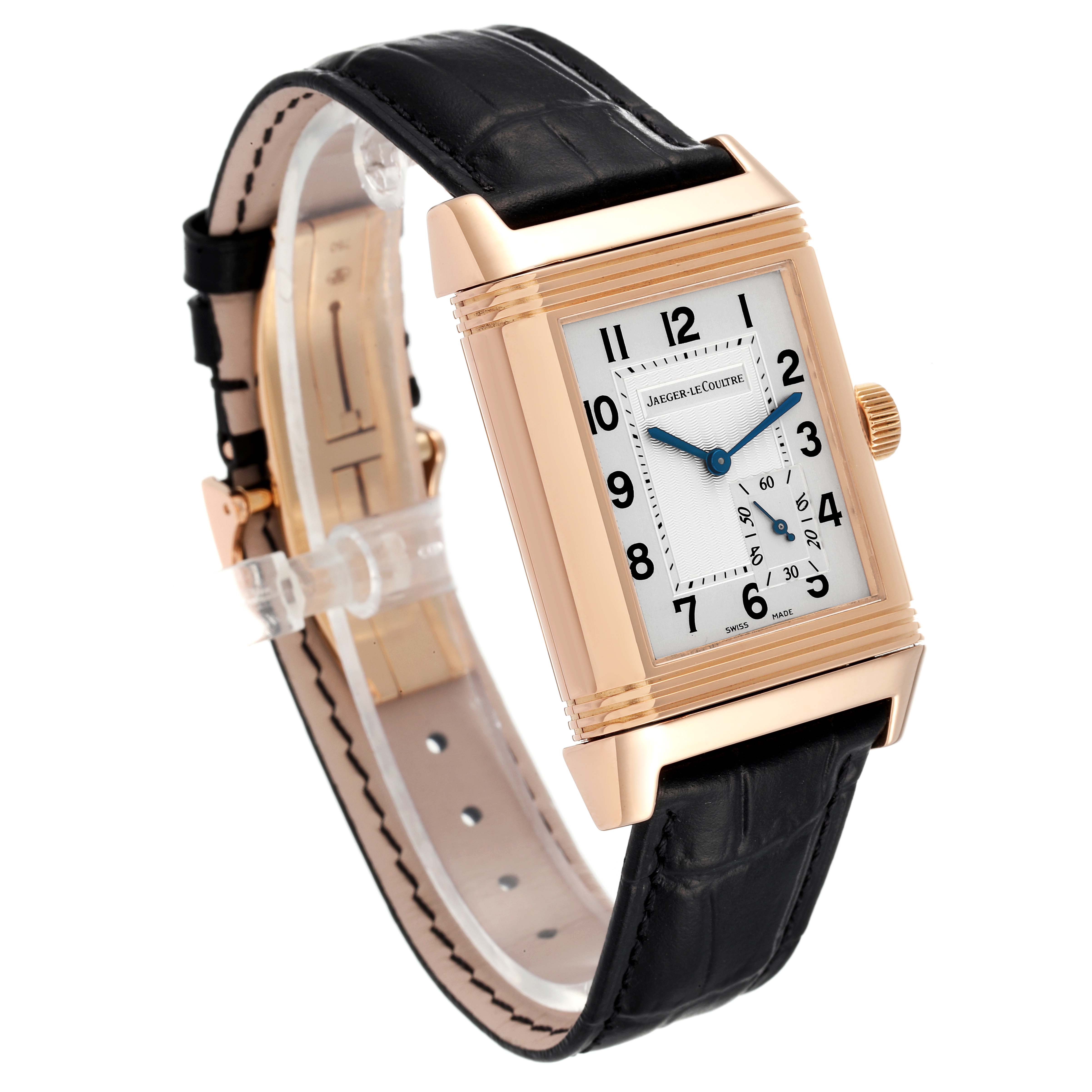 The Jaeger-LeCoultre Reverso watch is shown at a three-quarter angle, focusing on the rectangular case, dial, and leather strap.