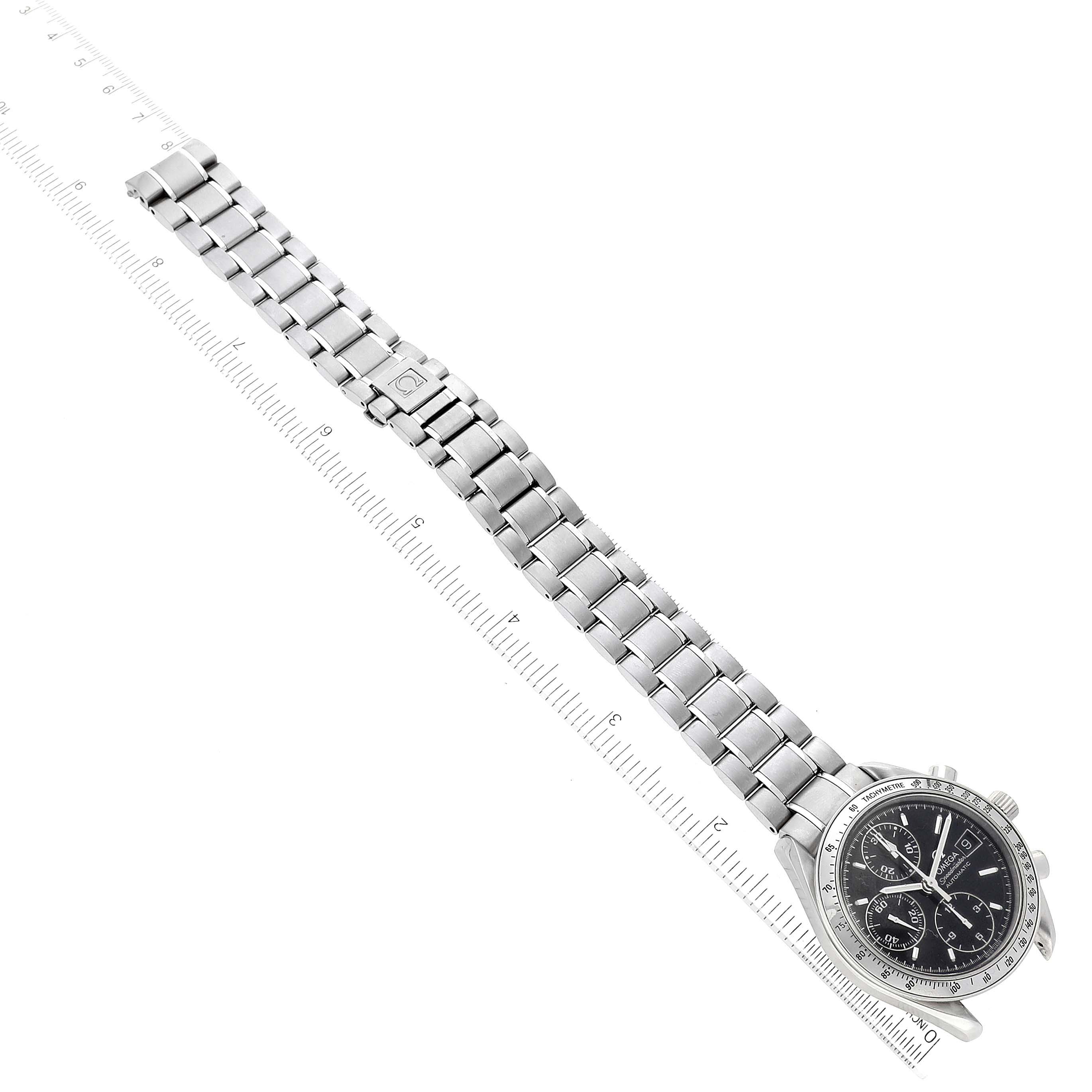 The Omega Speedmaster 3513.50.00 Men's Stainless Steel Black Dial watch is shown from an overhead angle, displaying its face, metal bracelet, and clasp beside a ruler.