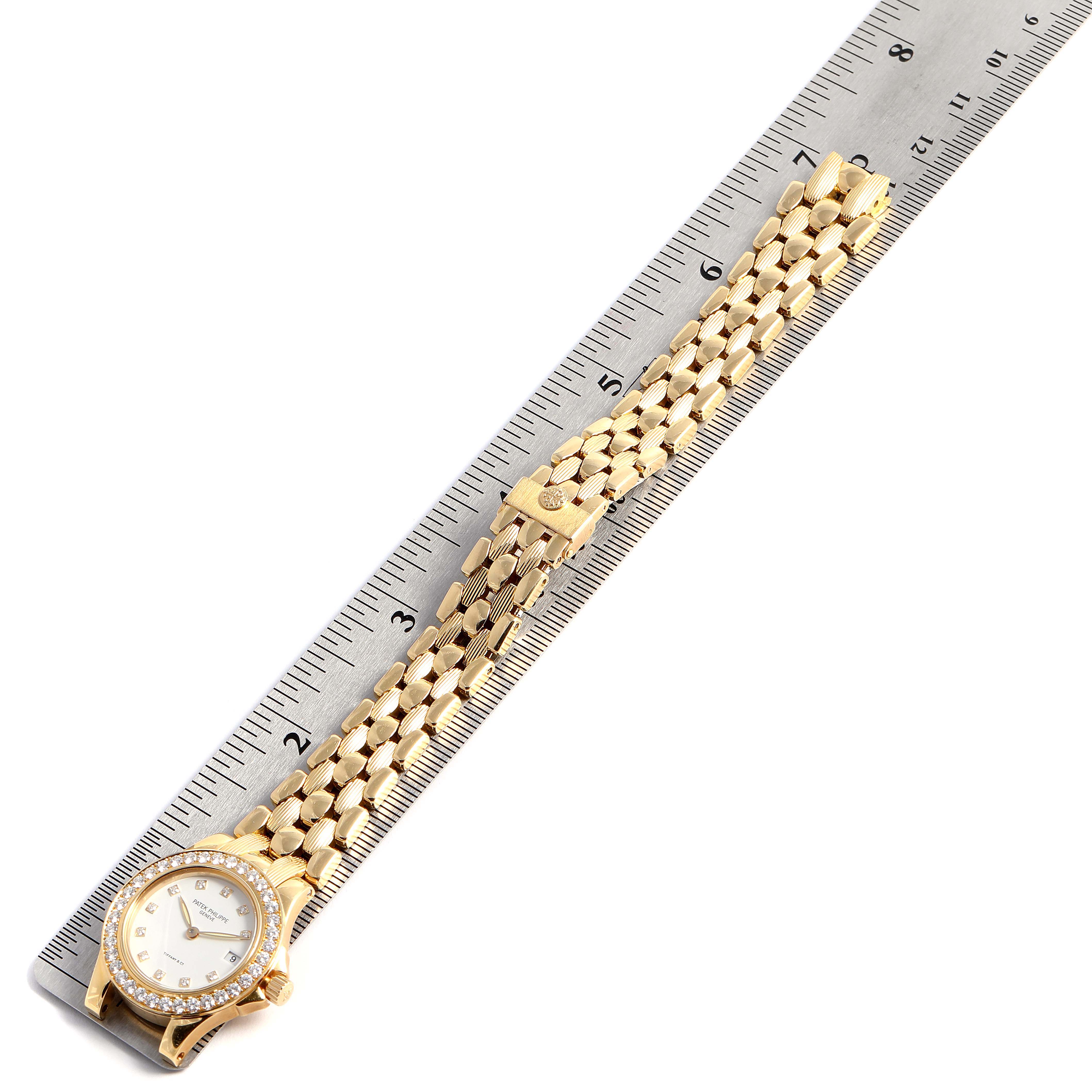 The image shows a gold Patek Philippe Neptune 4881--10J Women's Yellow Gold White Dial 4881--10J Women's Yellow Gold White Dial model watch laid flat next to a ruler, displaying the face, band, and clasp.