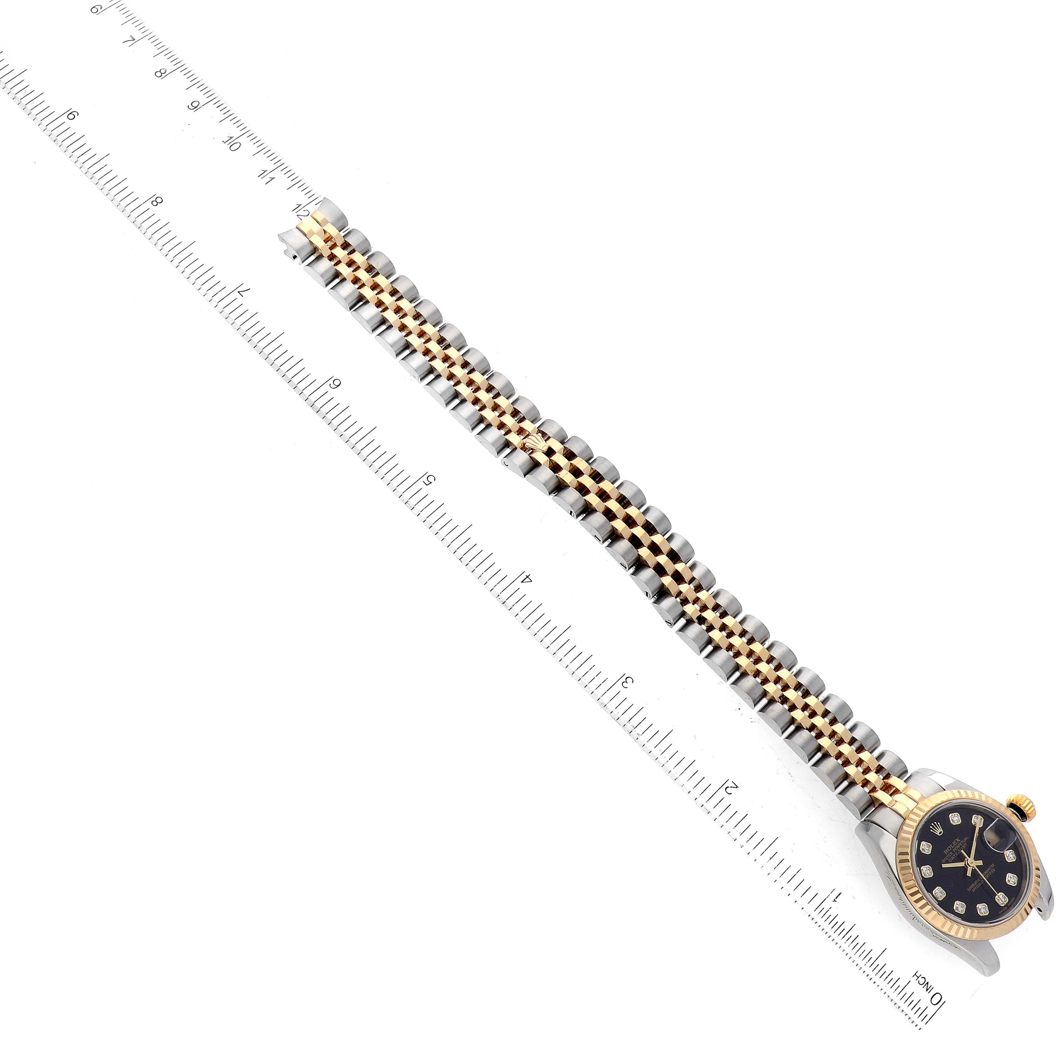 This image shows a top-down view of a Rolex Datejust 179173 Women's Steel and Gold (two tone) Black Dial 179173 Women's Steel and Gold (two tone) Black Dial watch, detailing the face and full length of the bracelet alongside a ruler.