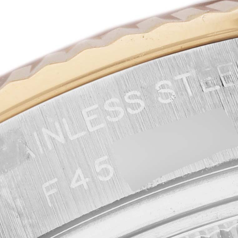 This close-up image shows the edge of the stainless steel and gold bezel of a Rolex Datejust 179173 Women's Steel and Gold (two tone) Black Dial 179173 Women's Steel and Gold (two tone) Black Dial watch, highlighting engraved text.