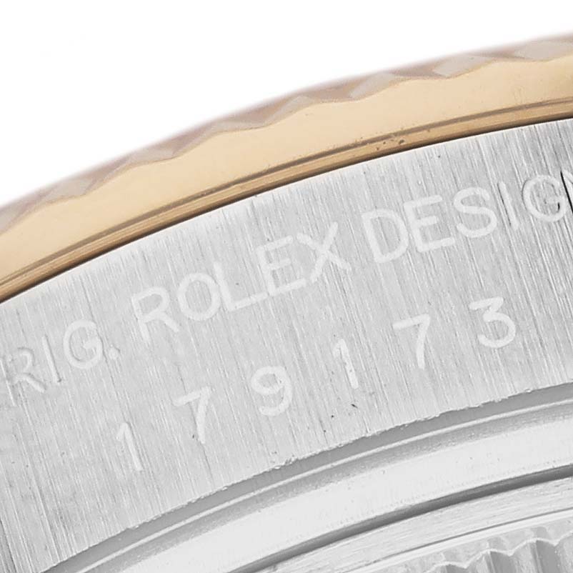 This close-up image of the Rolex Datejust 179173 Women's Steel and Gold (two tone) Black Dial 179173 Women's Steel and Gold (two tone) Black Dial watch shows the engraved text on the case and part of the fluted bezel.