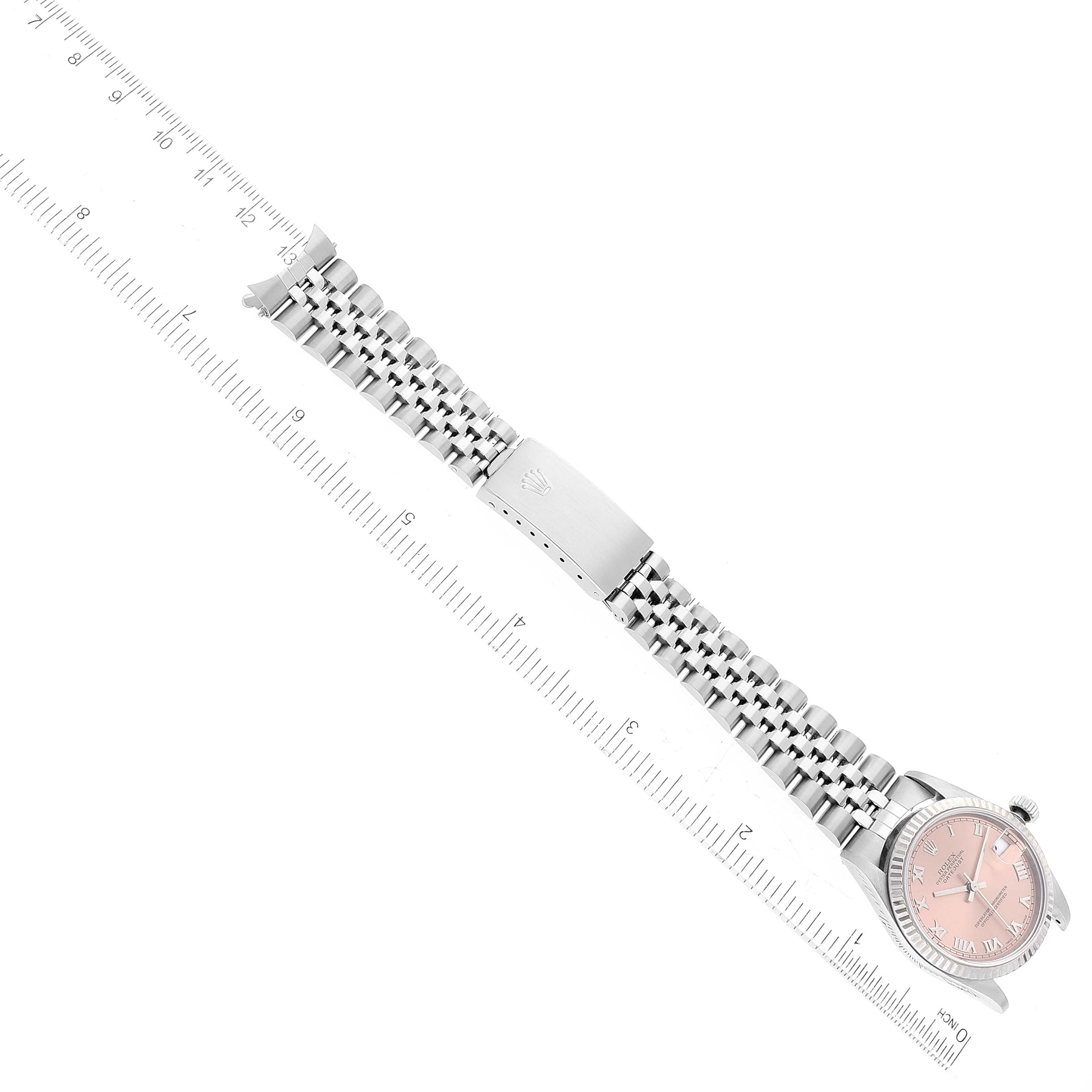The image shows a Mid-Size Rolex watch laid flat with a prominent view of its band and clasp, set against a ruler for scale.