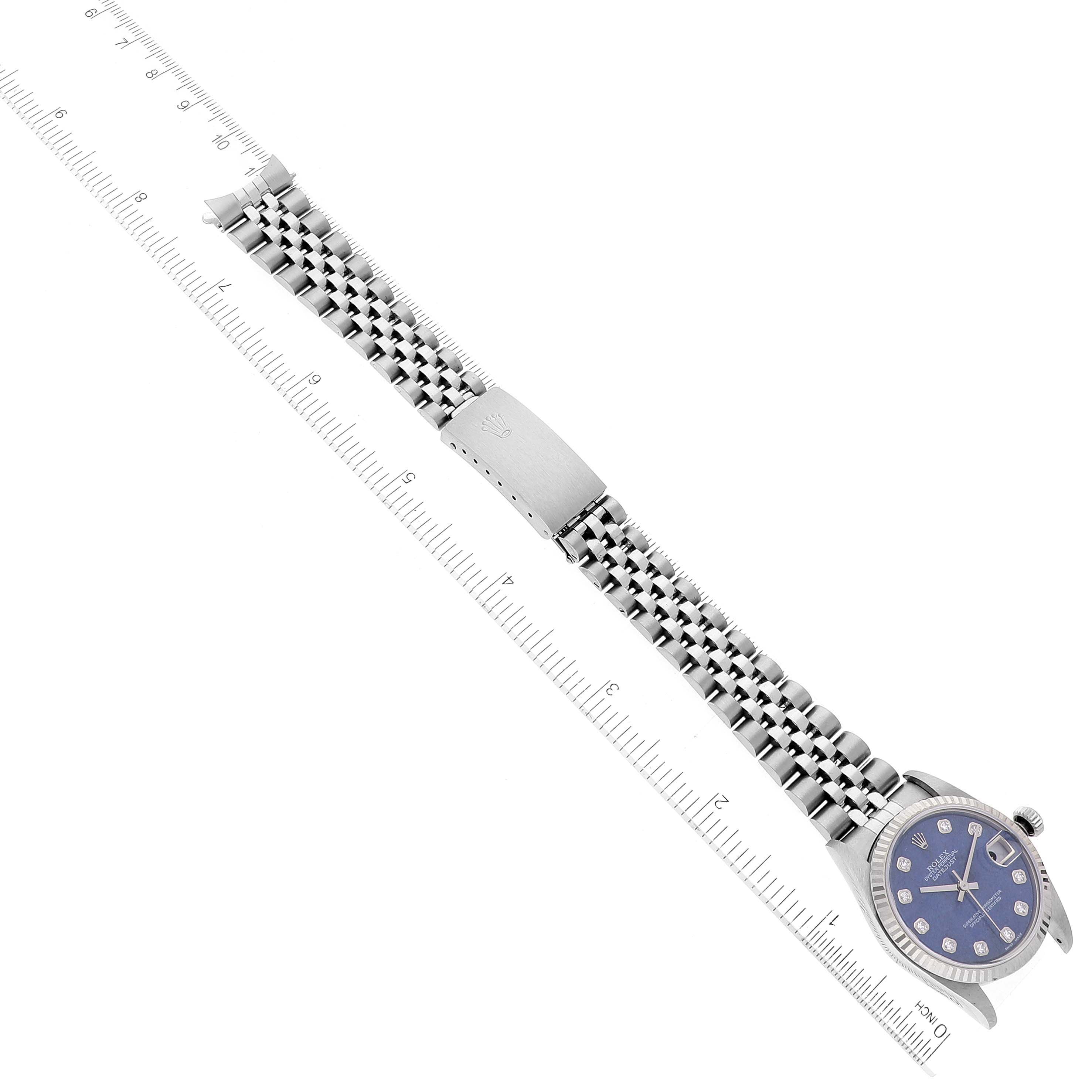 The image shows a straight-on view of a Mid-Size Rolex watch with a metal bracelet laid next to a ruler.