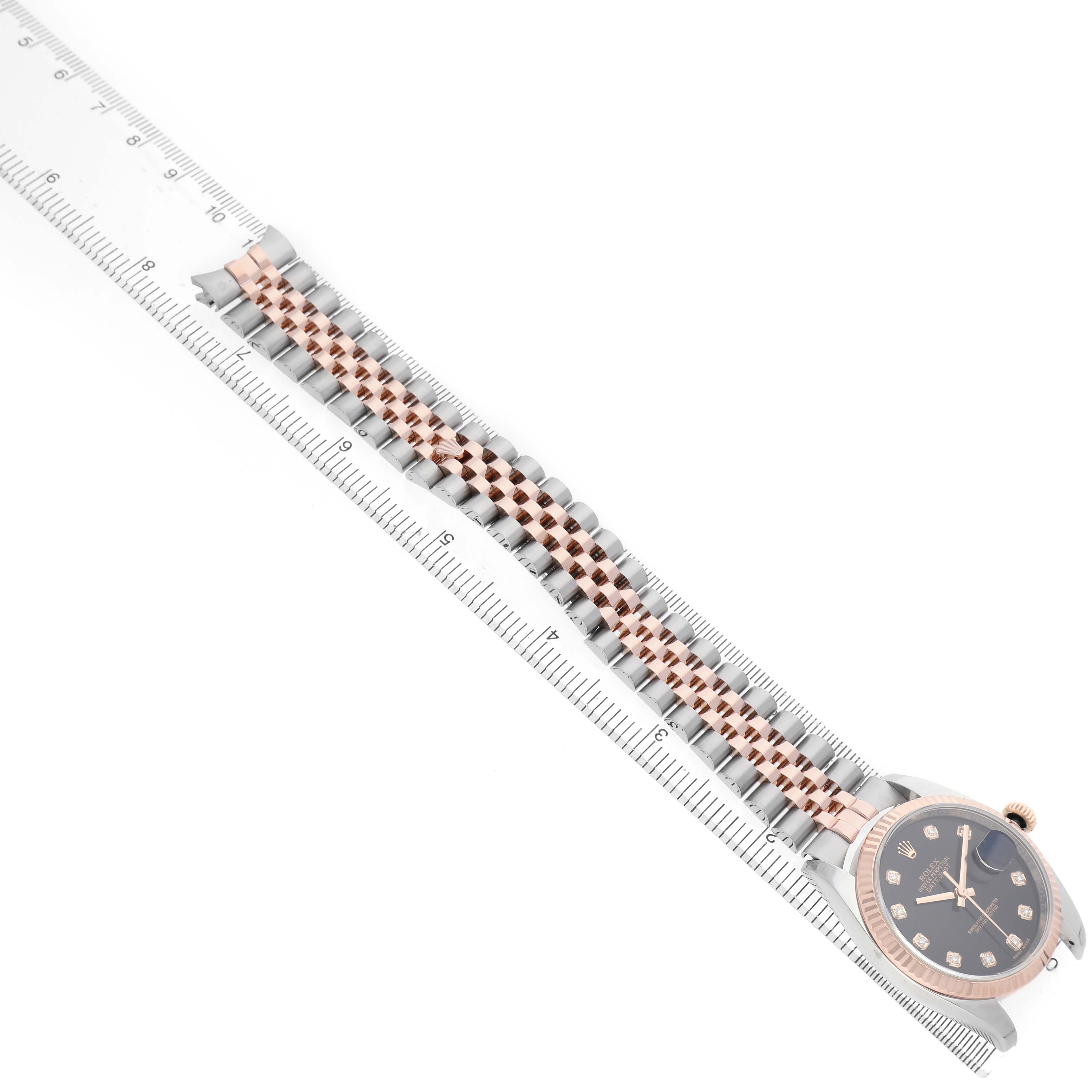The Rolex Datejust 116231 Men's Steel and Gold (two tone) Black Dial watch is shown from a top-down angle, highlighting its face, bezel, and bracelet laid alongside a ruler.