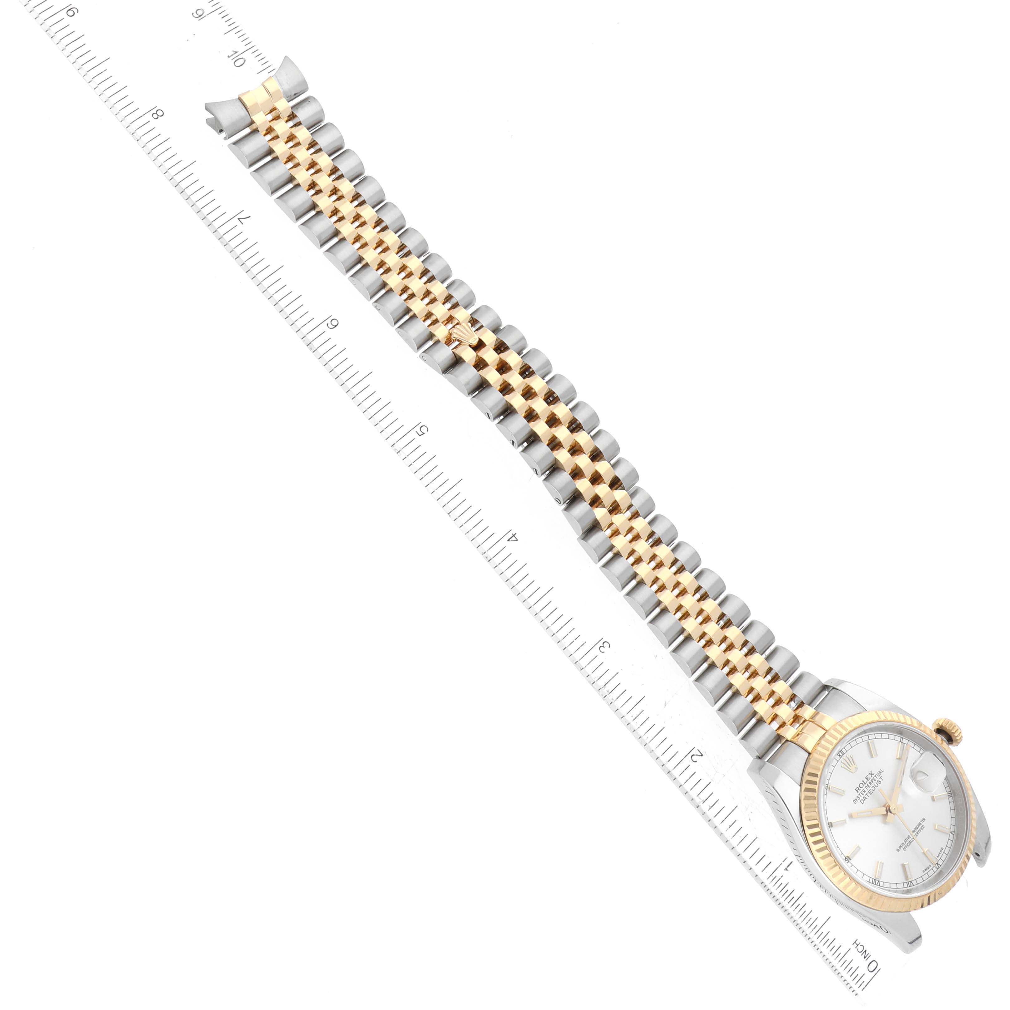 The image shows a Rolex Datejust 116233 Men
s Steel and Gold (two tone) Silver Dial 116233 Men
s Steel and Gold (two tone) Silver Dial watch from a top-down angle, highlighting the bracelet and dial against a ruler for scale.