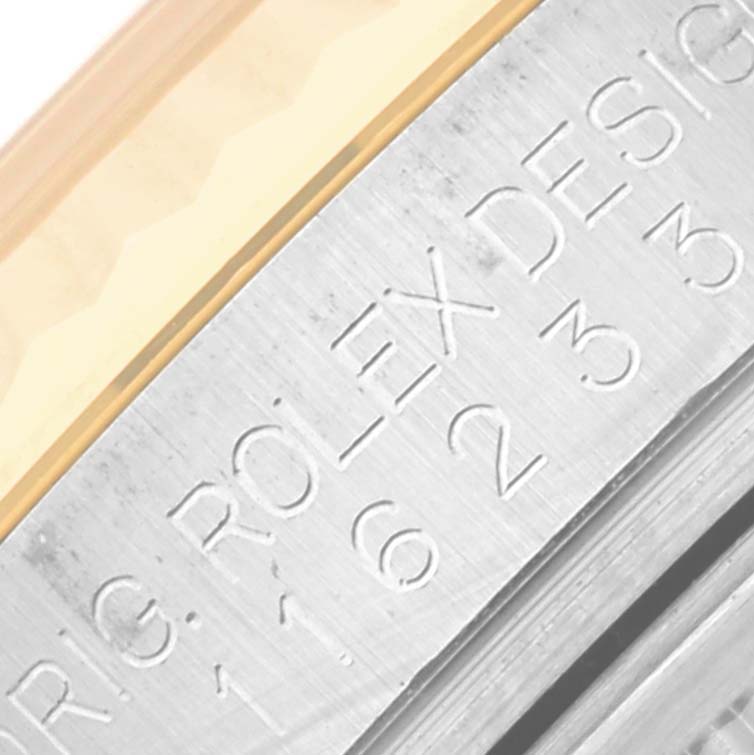 The image shows a close-up angle of the engraved bezel and the edge of the case of a Rolex Datejust 116233 Men
s Steel and Gold (two tone) Silver Dial 116233 Men
s Steel and Gold (two tone) Silver Dial watch.