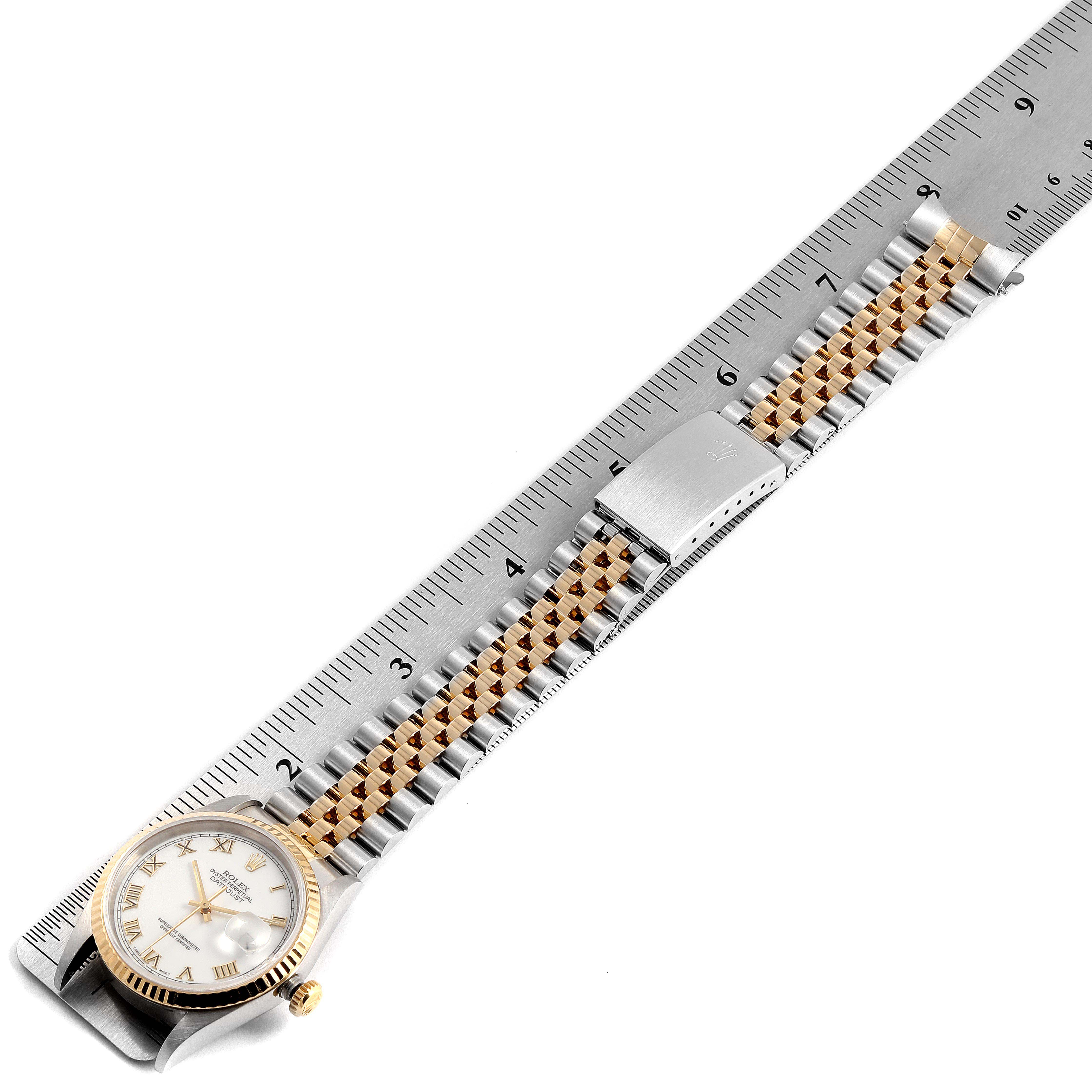 The Rolex Datejust 16233 Men's Steel and Gold (two tone) White Dial 16233 Men's Steel and Gold (two tone) White Dial watch is shown from a top-down angle, highlighting its face, bezel, and two-tone bracelet, next to a ruler.