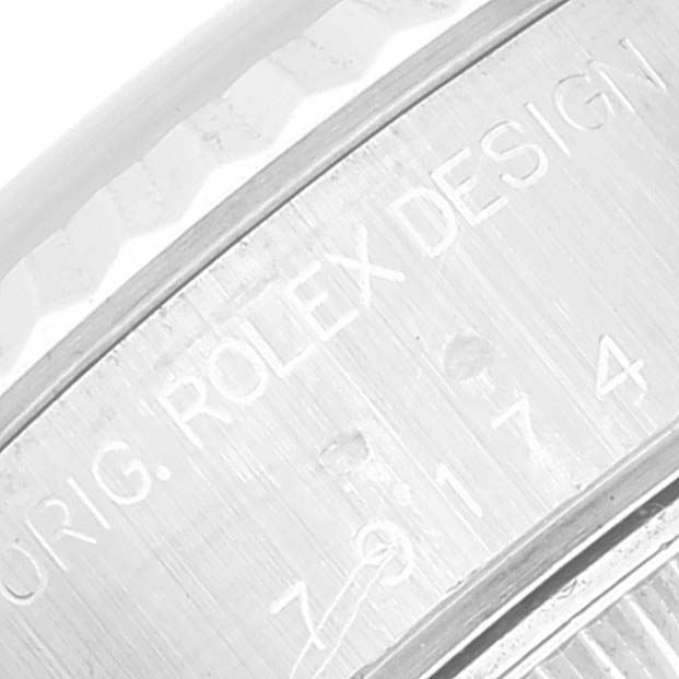 This image shows an extreme close-up of the engraved case side of a Rolex Datejust 79174 Women's Stainless Steel Black Dial 79174 Women's Stainless Steel Black Dial watch with the text "ROLEX DESIGN."