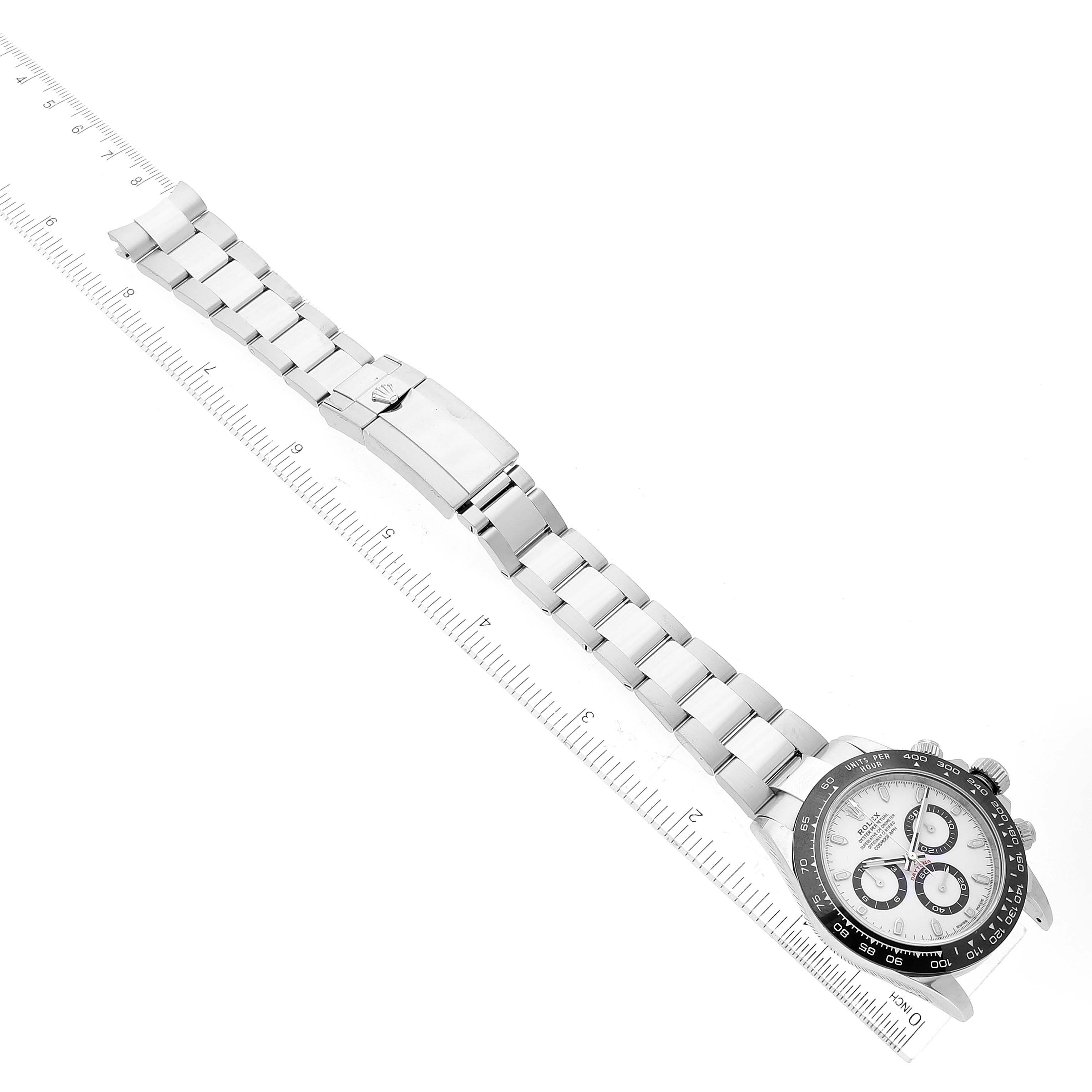 The Rolex Daytona 116500 Men's Stainless Steel White Dial 116500 Men's Stainless Steel White Dial watch is shown at a slight diagonal angle, displaying the face and full metal bracelet against a ruler for scale.