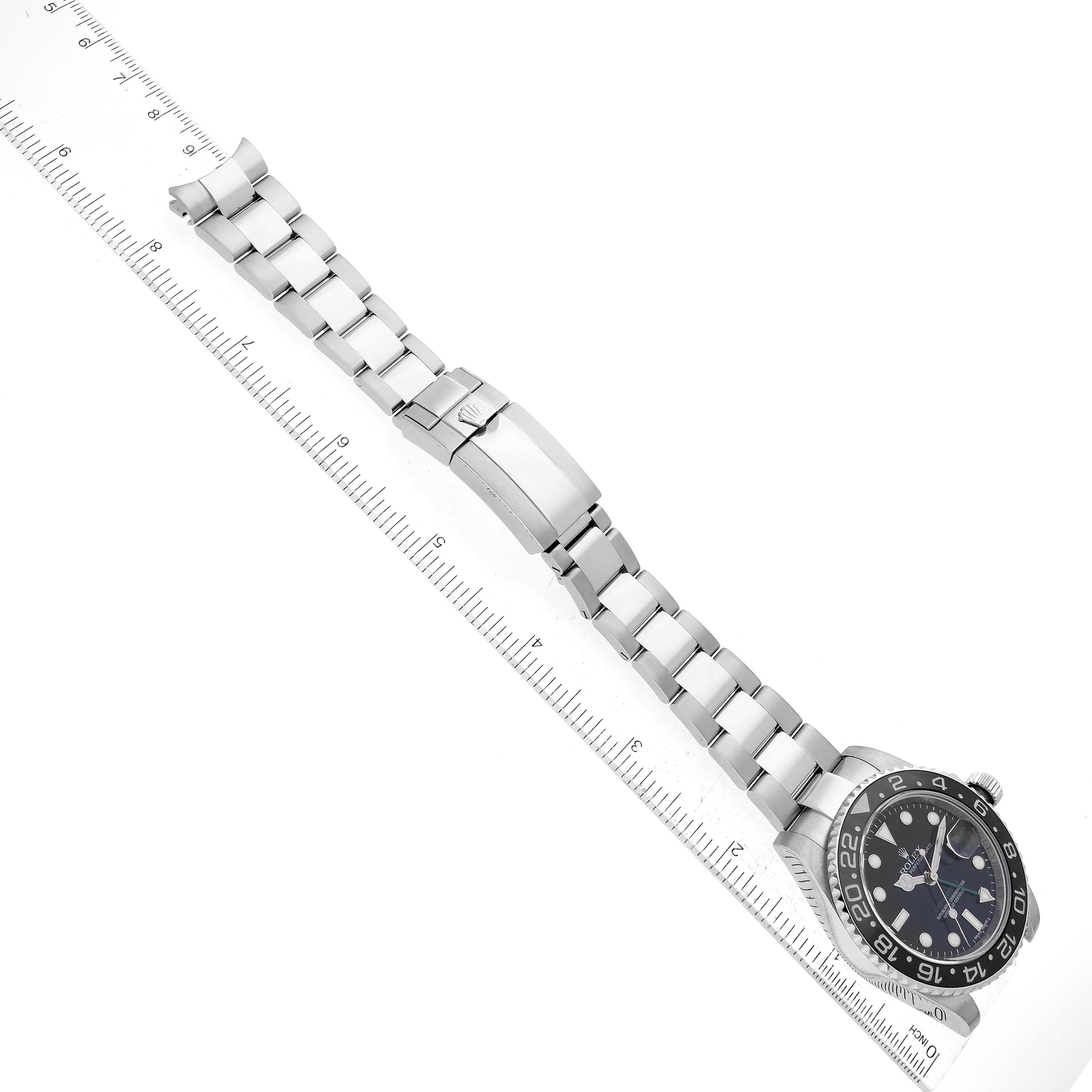 The image shows a Rolex GMT-Master 116710 Men
s Stainless Steel Black Dial 116710 Men
s Stainless Steel Black Dial watch positioned at an angle, featuring the face/dial, bezel, bracelet, and clasp, next to a ruler for scale.