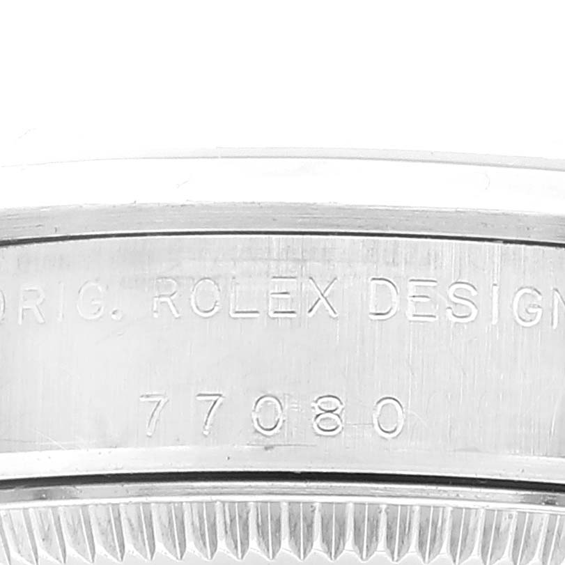 The image shows a close-up of the side of a Rolex Mid-Size 77080 Women's Stainless Steel Black Dial 77080 Women's Stainless Steel Black Dial model, highlighting the engraved serial number and "ORIG. ROLEX DESIGN" text.