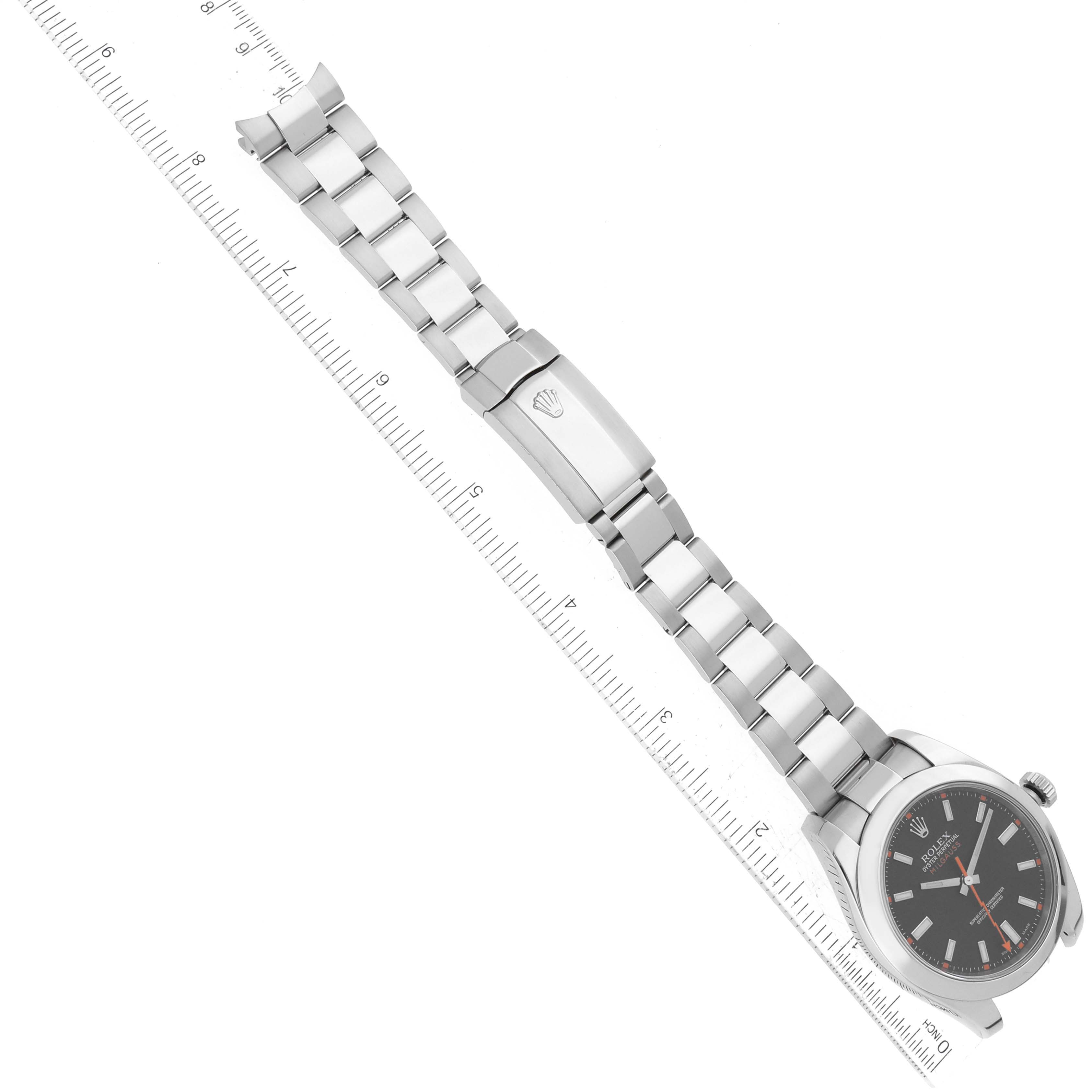 The image shows a top-down view of a Rolex Milgauss 116400 Men
s Stainless Steel Black Dial 116400 Men
s Stainless Steel Black Dial watch, displaying the watch face, bracelet, and clasp alongside a ruler for scale.