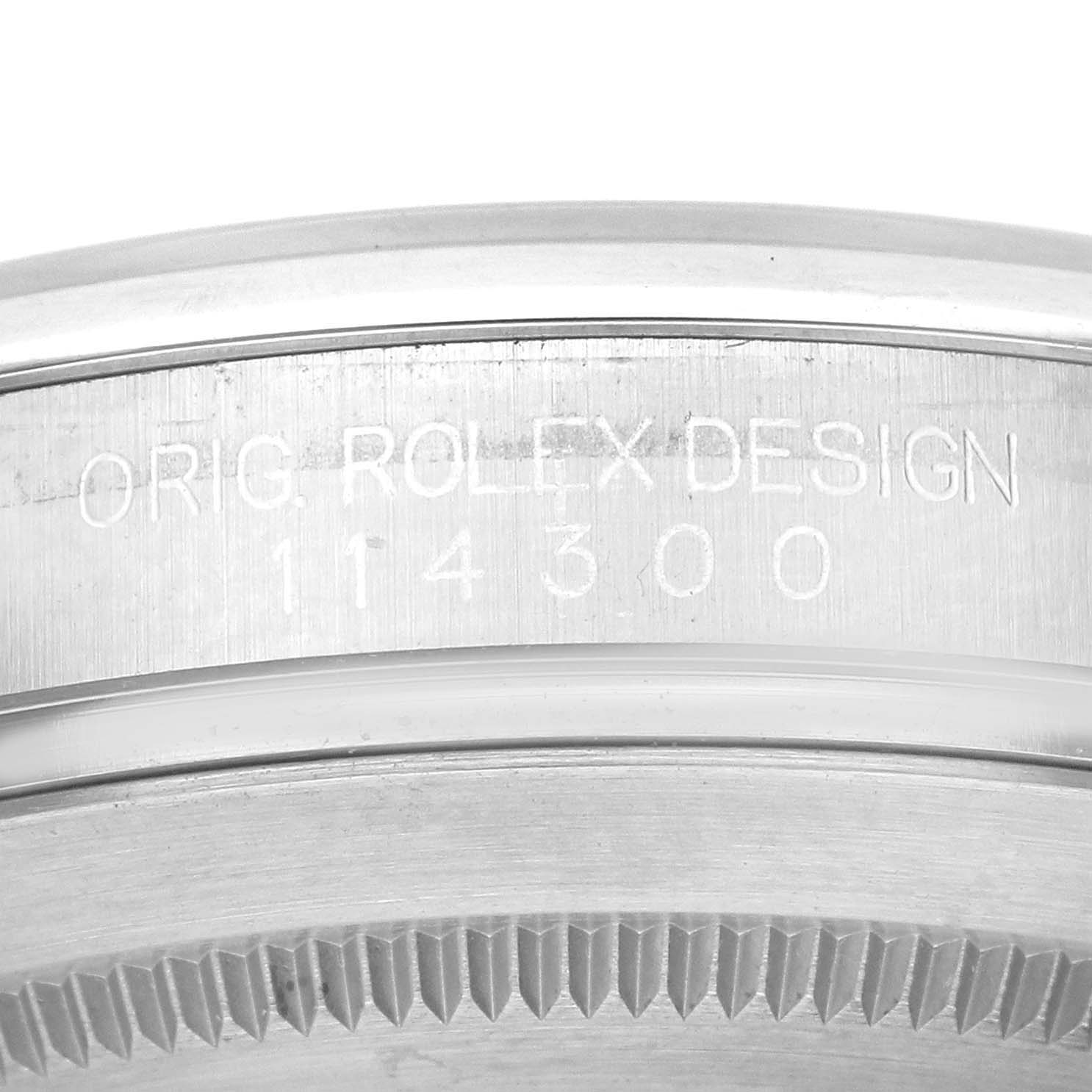 This close-up shows the engraved inner bezel of a Rolex Oyster Perpetual 114300 Men's Stainless Steel Black Dial 114300 Men's Stainless Steel Black Dial watch, displaying the model number 114300.