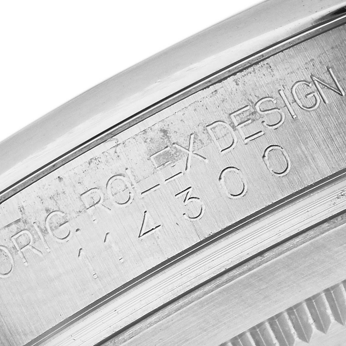 This image shows a close-up angle of the engraved serial number and branding on the side of a Rolex Oyster Perpetual 114300 Men's Stainless Steel Grey Dial 114300 Men's Stainless Steel Grey Dial watch.