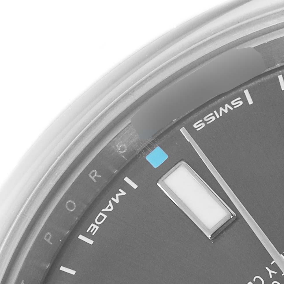 The image shows a close-up view of the dial and part of the bezel of a Rolex Oyster Perpetual 114300 Men's Stainless Steel Grey Dial 114300 Men's Stainless Steel Grey Dial watch.