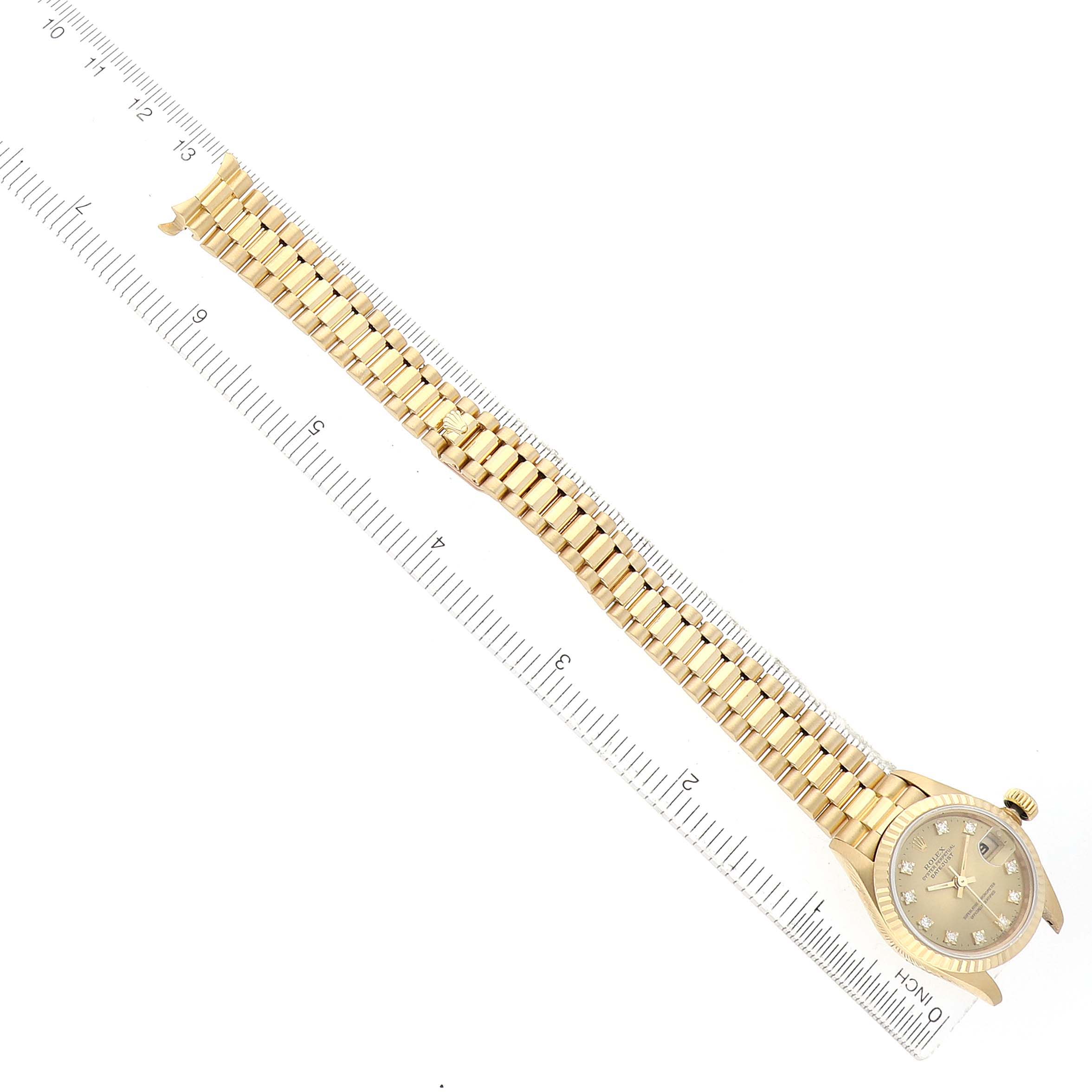 The Rolex President 69178 Women's Yellow Gold Champagne Dial model watch is shown from a top view, including the dial, bezel, and full bracelet next to a ruler.