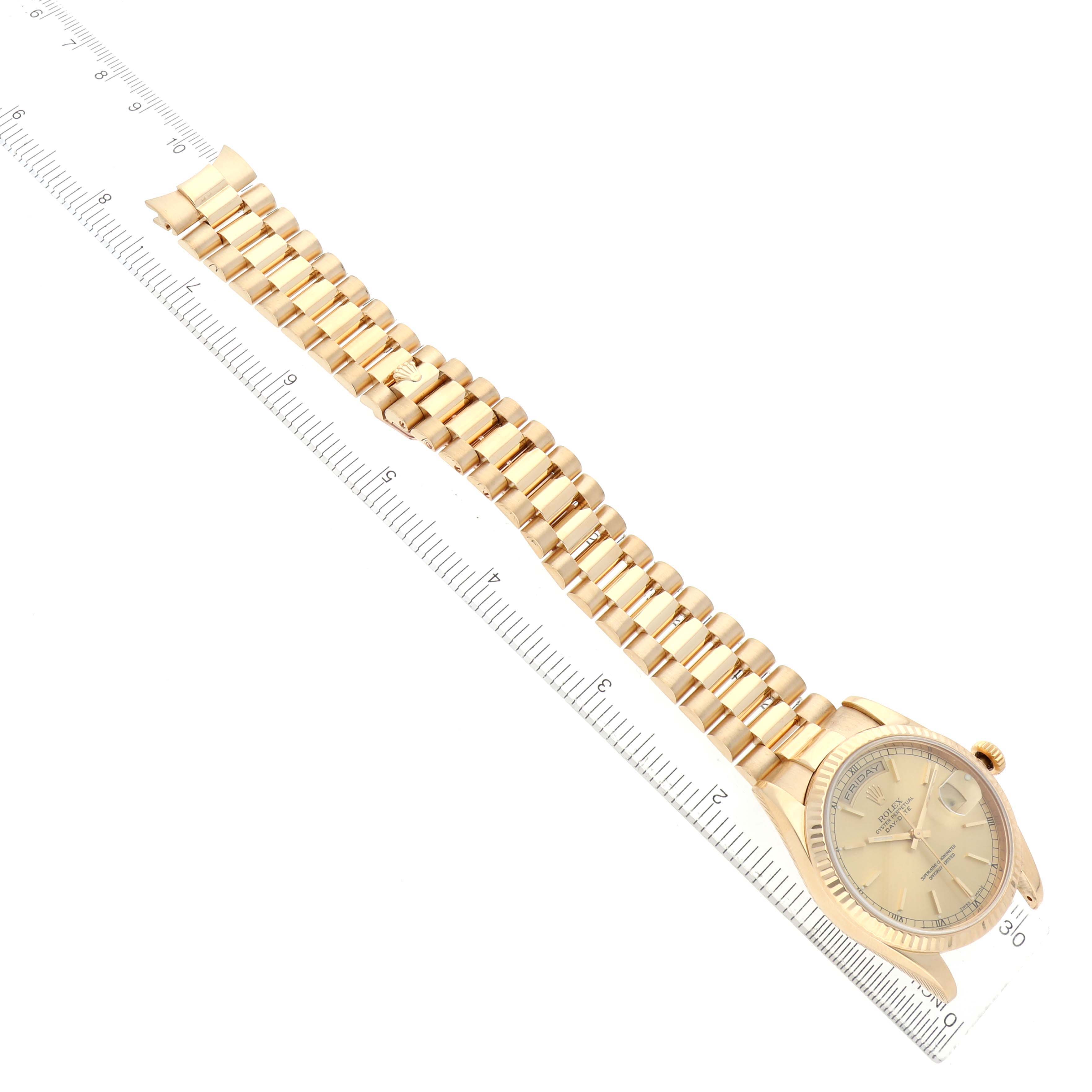 The Rolex President 118238 Men's Yellow Gold Champagne Dial model is shown at an angled view displaying the full watch face and gold bracelet, next to a ruler.
